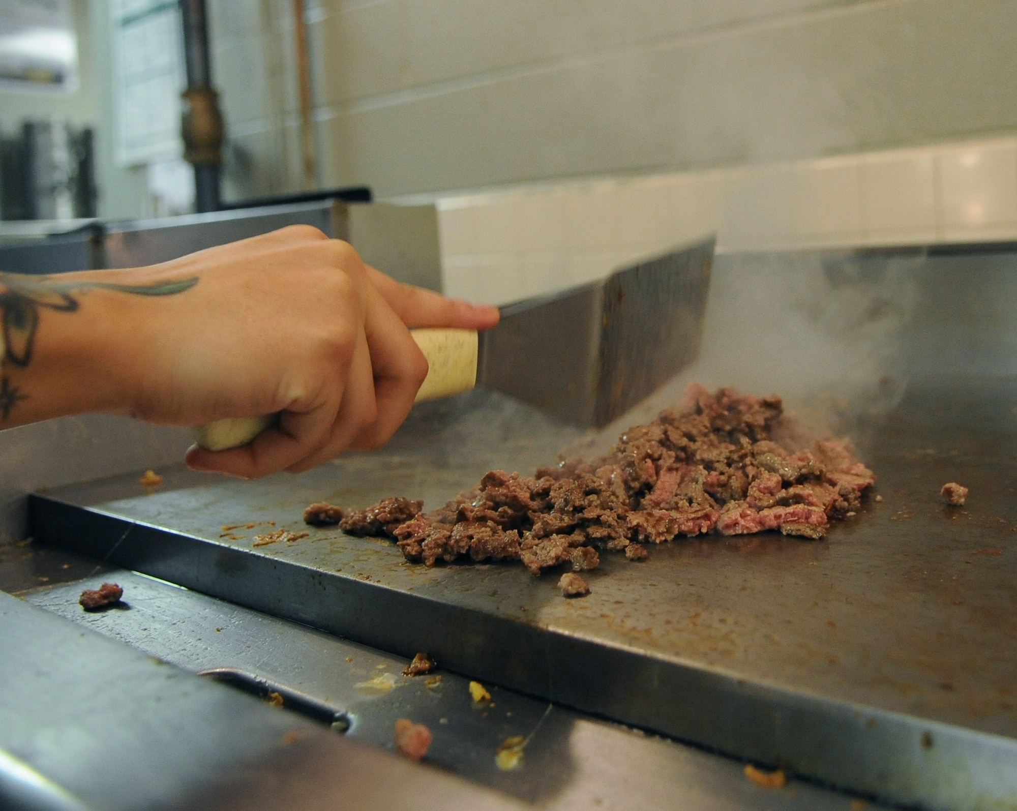 Senior Airman Ashly Williams, 2nd Force Support Squadron food services journeyman, chops up ground beef on a grill at the Touch and Go Flight Kitchen on Barksdale Air Force Base, La., Nov. 15. The flight kitchen provides meals for Airmen and aircrew to save them time and money. (U.S. Air Force photo/Senior Airman Micaiah Anthony)(RELEASED) 