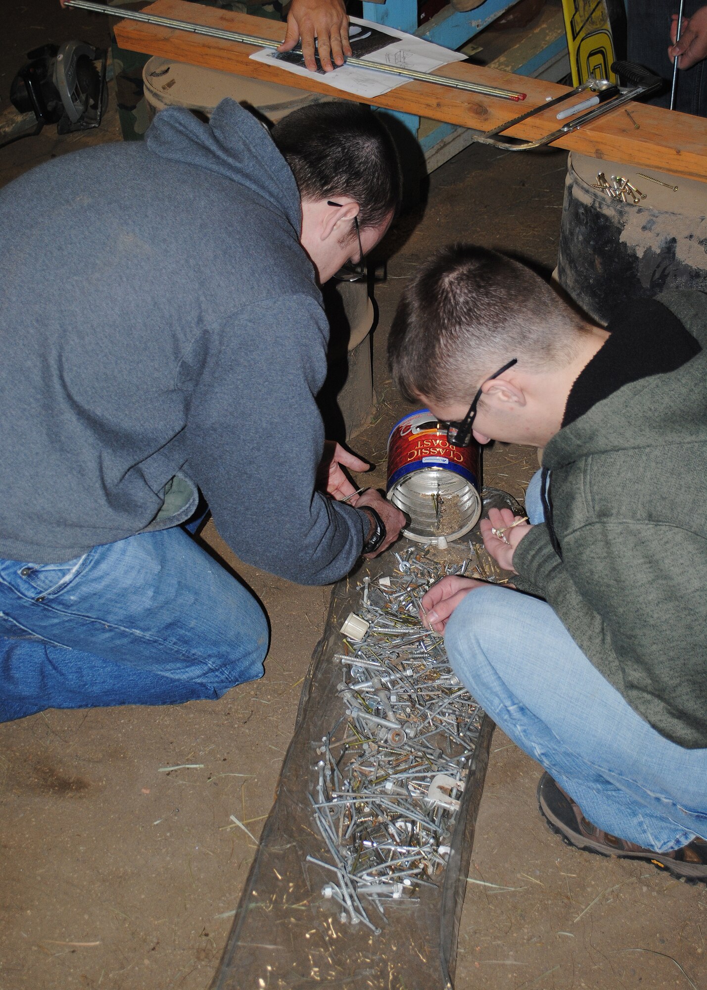 1st Lt. Benjamin Hunt, left, 10th Missile Squadron deputy combat crew commander, and 1st Lt. Garrett George, 10th MS  combat crew commander, sort through nails to find the size they need.  As one of the projects, Team Malmstrom members used four snowboards and other wood to make two benches for the participants of Eagle Mount to use during ski/snowboard outings.  (U.S. Air Force photo/Airman 1st Class Cortney Paxton)