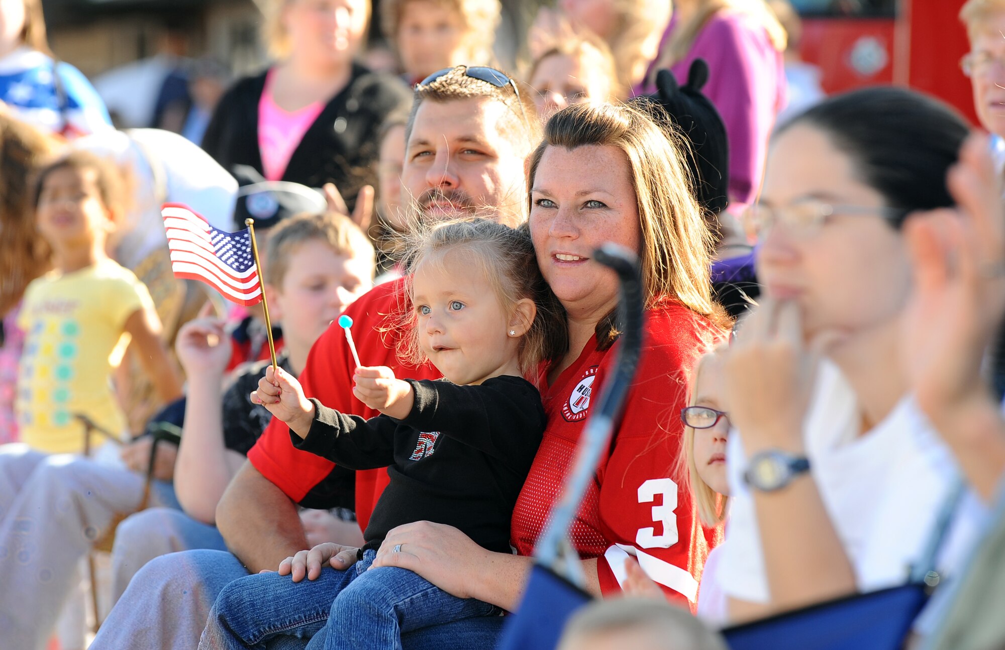 Josie Oseka along with her mom, Channon, and dad, Antone, watch the Veterans Day parade together in Bellevue, Neb., Nov. 10.  The annual parade draws hundreds of metro area families to show their support of our nation’s veterans. (U.S. Air Force Photo by Josh Plueger/Released)