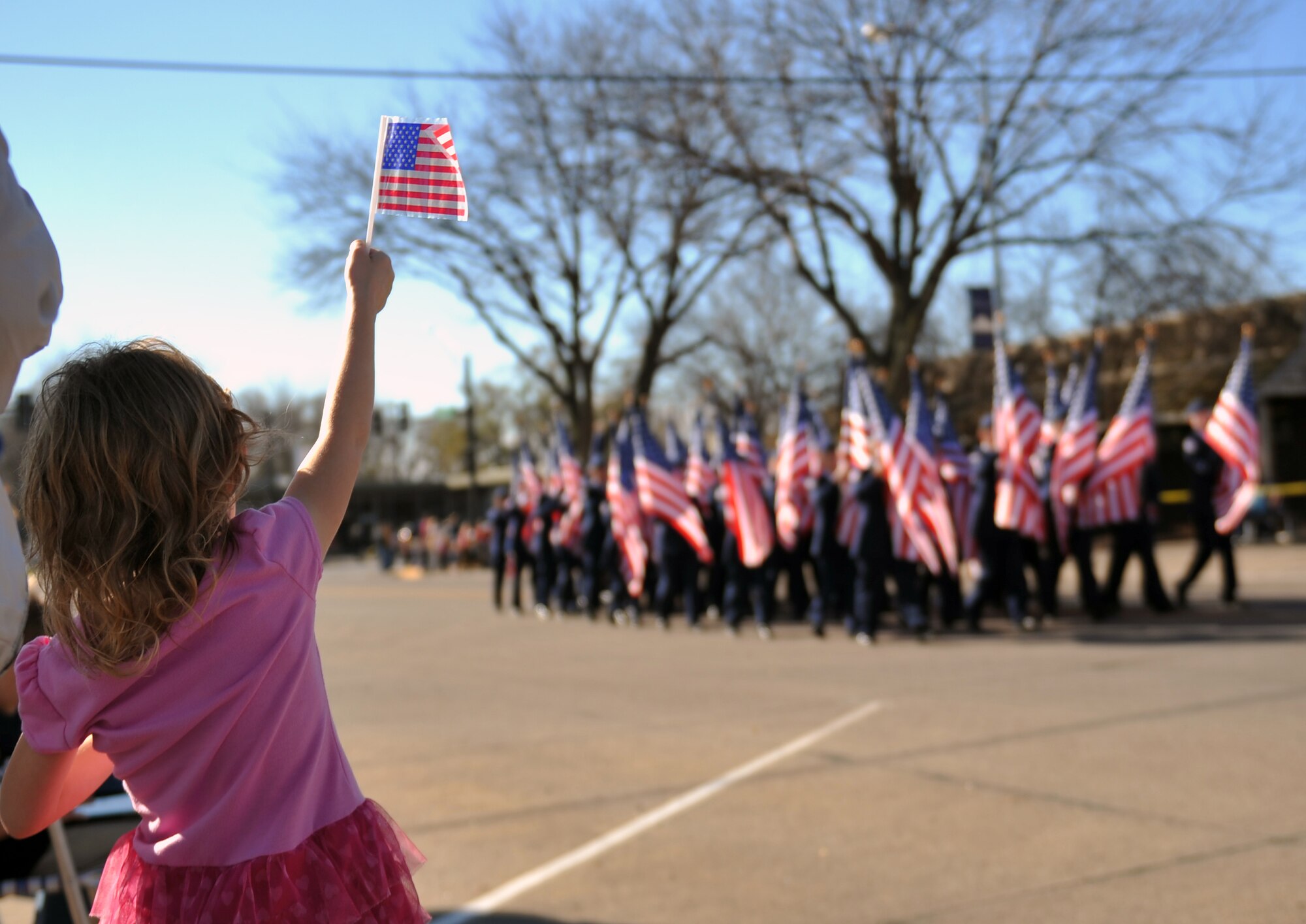 Holly Smith, daughter of U.S. Air Force Master Sgt. Raymond Taylor, 55th Medical Support Squadron, holds her flag up with pride as the Junior ROTC marches by in the 2012 Veterans Day parade in Bellevue, Neb. Nov. 10. Team Offutt joined with the Bellevue community to honor veterans. (U.S. Air Force photo by Jeff W. Gates/Released)