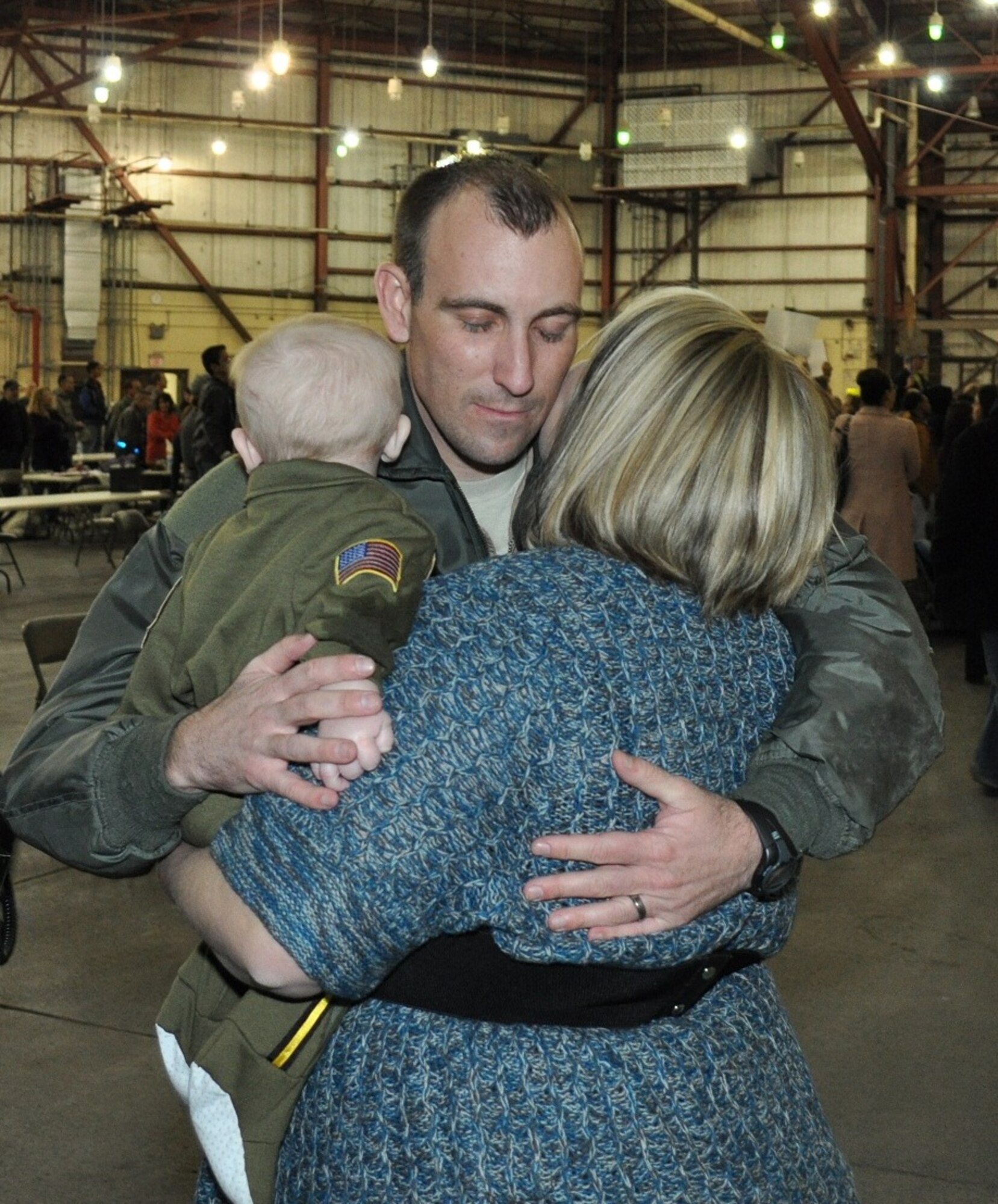 Master Sgt. Gabriel Richardson, an Air Surveillance Technician assigned to the 970th Airborne Air Control Squadron, embraces wife Candice and his six-month-old son for the first time. Richardson returned Sunday with 89 reservists from the 513th Air Control Group after a six-month deployment to Southwest Asia. Collin Richardson was born just a few days after Master Sgt. Richardson left on the deployment. (U.S. Air Force Photo by Capt. Jon Quinlan)