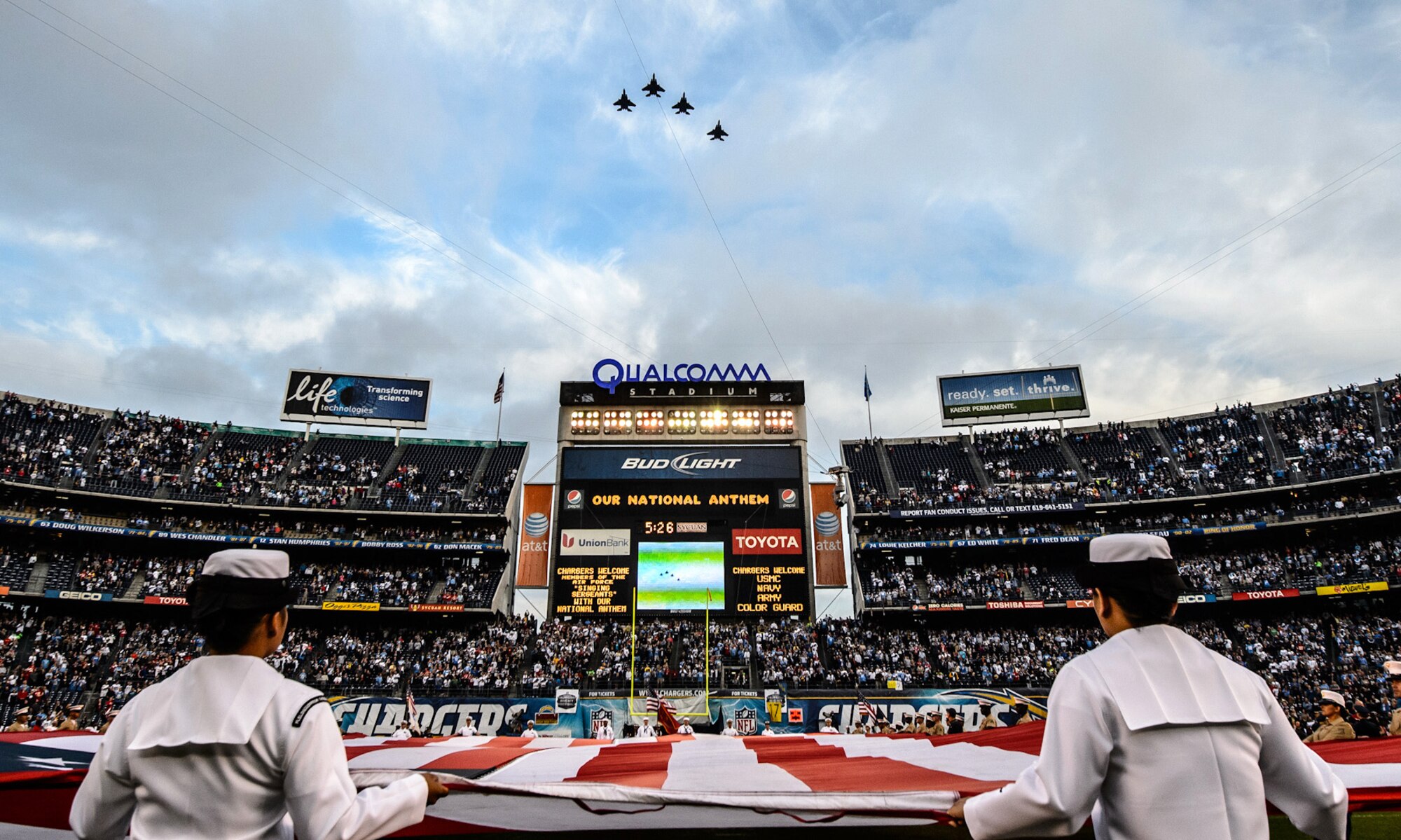 U.S. Navy Seamen hold a United States flag on the field of Qualcomm Stadium, San Diego, Calif., while four F-15E Strike Eagles from Mountain Home Air Force Base, Idaho, perform a flyover Nov. 1, 2012. The Chargers beat the Kansas City Chiefs 31-13. (Courtesy photo)