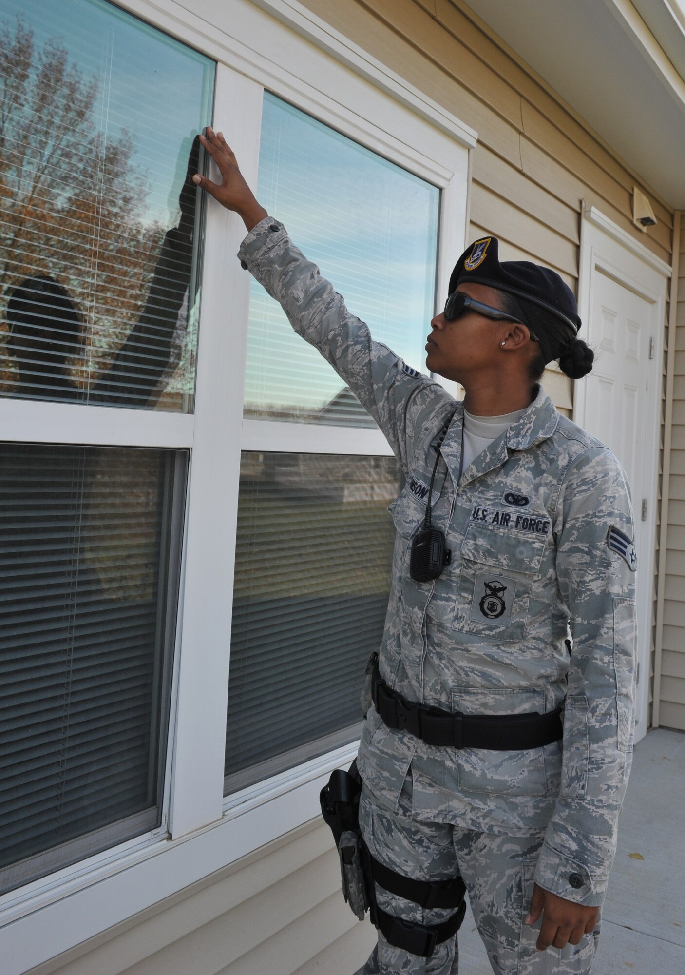 Senior Airman Keena Johnson, 509th Security Forces Squadron Law Enforcement, checks a window for broken glass which can be a sign of a forced entry during her shift at Whiteman Air Force Base housing Nov. 13. Base residents can sign up for Operation Quarters Watch before they leave for vacation and 509th SFS will make a physical check on their homes. (U.S. Air Force photo/Heidi Hunt) (Released)