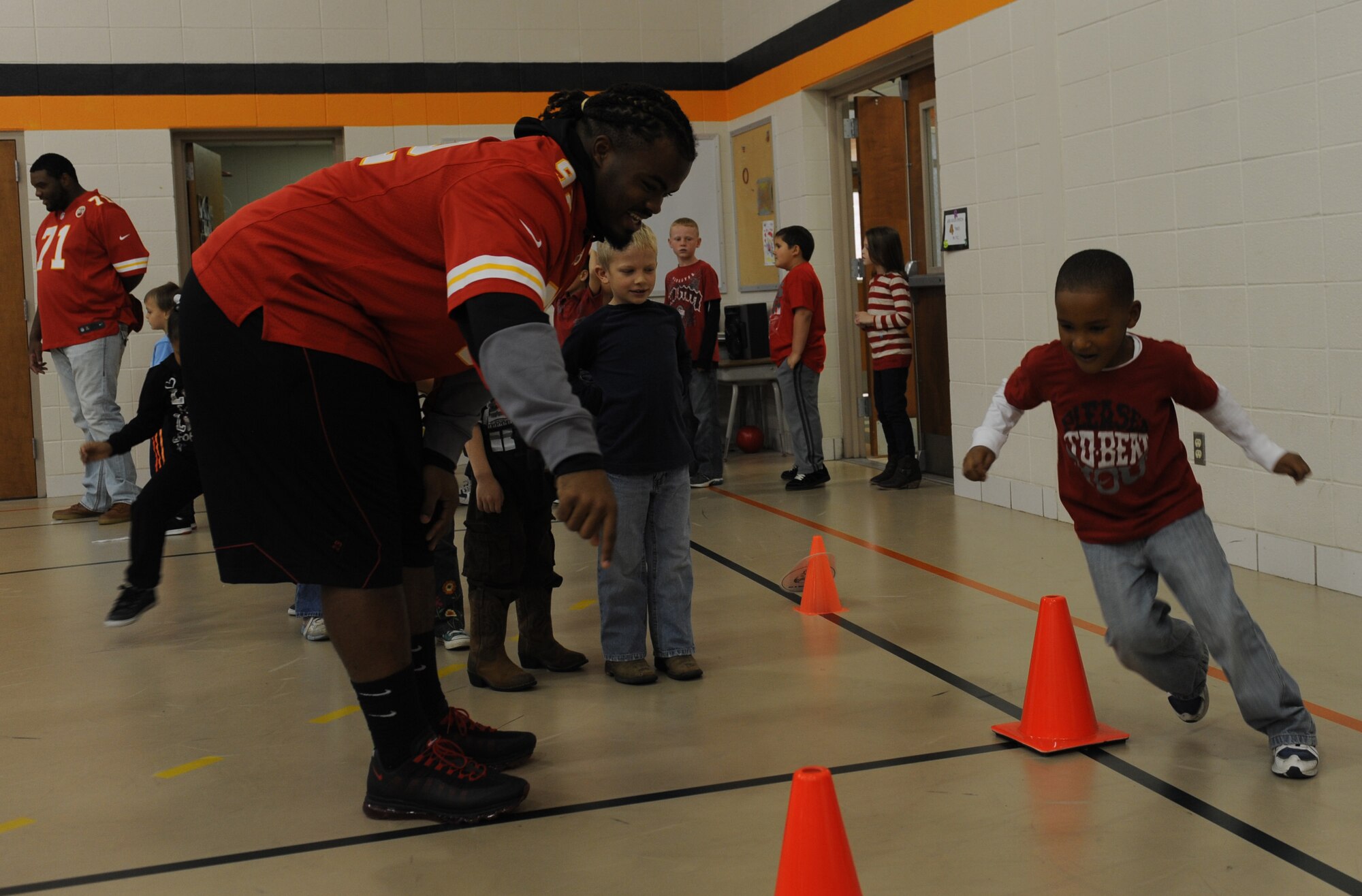 WHITEMAN AIR FORCE BASE -- Dontari Poe, Kansas City Chiefs nose tackle, runs a child through a football drill during the Play 60 event at Whiteman Elementary School, Nov. 6. The Play 60 initiative is a National Football League’s campaign aimed at encouraging kids to be active for 60 minutes a day in order to combat childhood obesity. (U.S. Air Force photo/Airman 1st Class Bryan Crane)