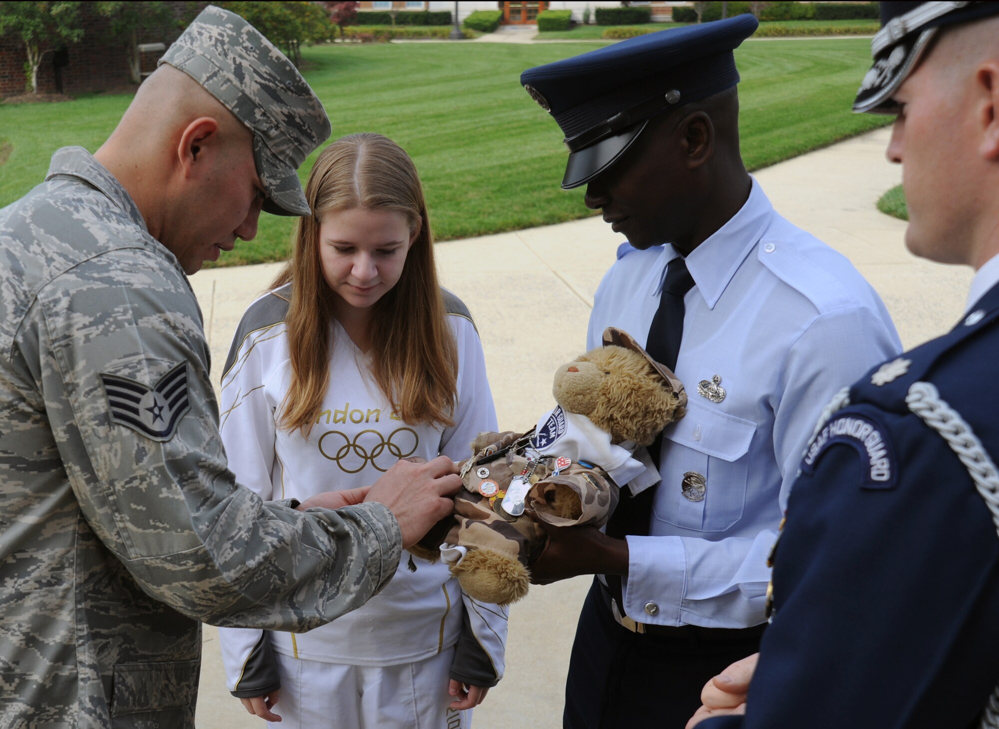Members of the U.S. Air Force Honor Guard pin another peice of military flair on Hero the bear for Bailey Reese during her visit to the United States Air Force Honor Guard campus at Joint Base Anacostia-Bolling, D.C., Oct. 24.  Bailey was one of 30 selected to run the Olympic torch for America at the 2012 Games in London. (U.S. Air Force photo/Staff Sgt. Torey Griffith)