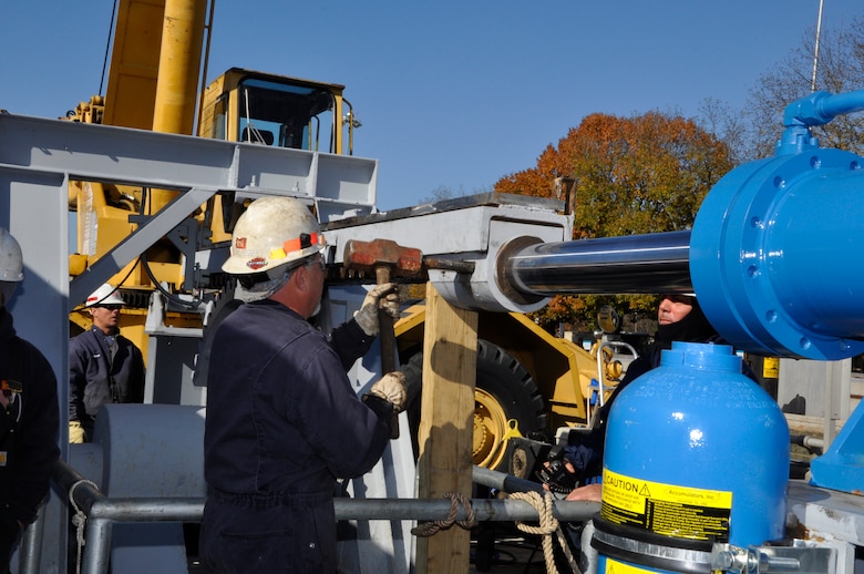 Jimmy Reeves, center, mechanic, hammers in a wedge Nov. 13, 2012 under the watchful eyes of Ross Cunningham, left,  lock and dam equipment  mechanic supervisor, and Greg Cox, right, chief of maintenance section, U.S. Army Corps of Engineers Nashville District. The wedge connects the new cylinder to the rack on the upper river wall machinery at Cheatham Lock, Ashland City, Tenn. Upper river valves fill the lock chamber to lake level and lower river valves lower it to tailwater level. (USACE photo by Fred Tucker)