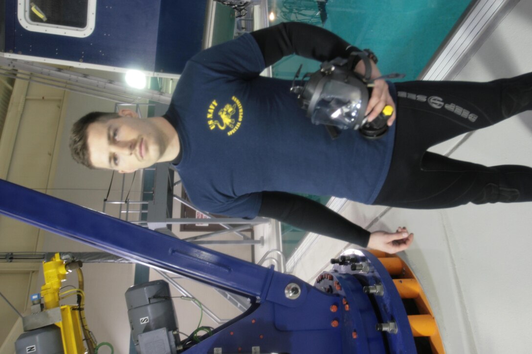 Petty Officer 3rd Class Jeff H. Baker, A Navy Diver with the Aviation Survival Training Center Cherry Point, poses with his dive gear in front of the dunker at the ASTC training pool.