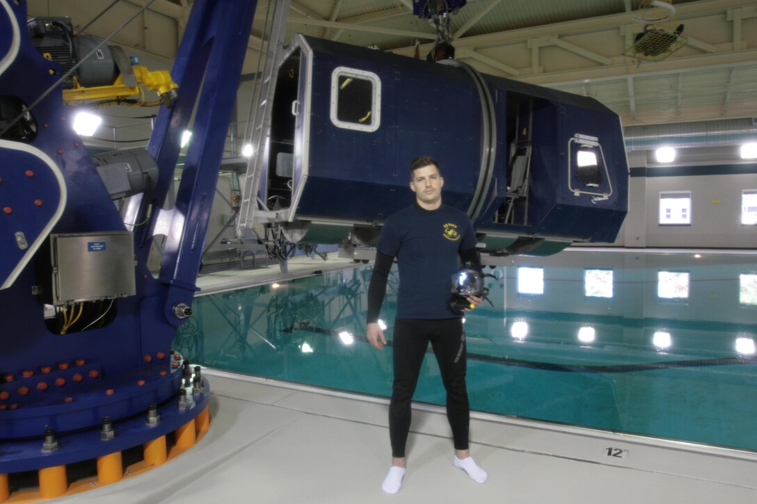 Petty Officer 3rd Class Jeff H. Baker, a Navy Diver with Aviation Survival Training Center Cherry Point, poses in front of the dunker at the ASTC training pool