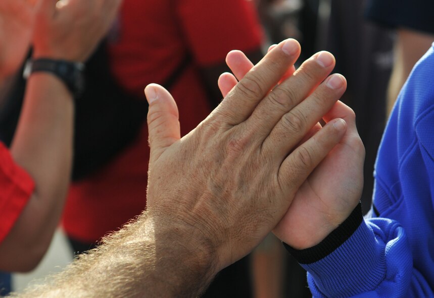 A volunteer high-fives an athlete participating in the 13th annual Kadena Special Olympics as they arrive during the KSO opening ceremonies on Kadena Air Base, Japan, Nov. 17, 2012. More than 1,500 artists and athletes participated in a variety of events ranging from 200 and 300 meter races, tennis skills and floor hockey to soccer skills and ground golf during the 13th Annual KSO. This year marks the 13th Annual KSO, a sporting event dedicated to enriching the lives of special-needs individuals while strengthening U.S. - Okinawa relationships. (U.S. Air Force photo/Tech. Sgt. Jocelyn Rich)