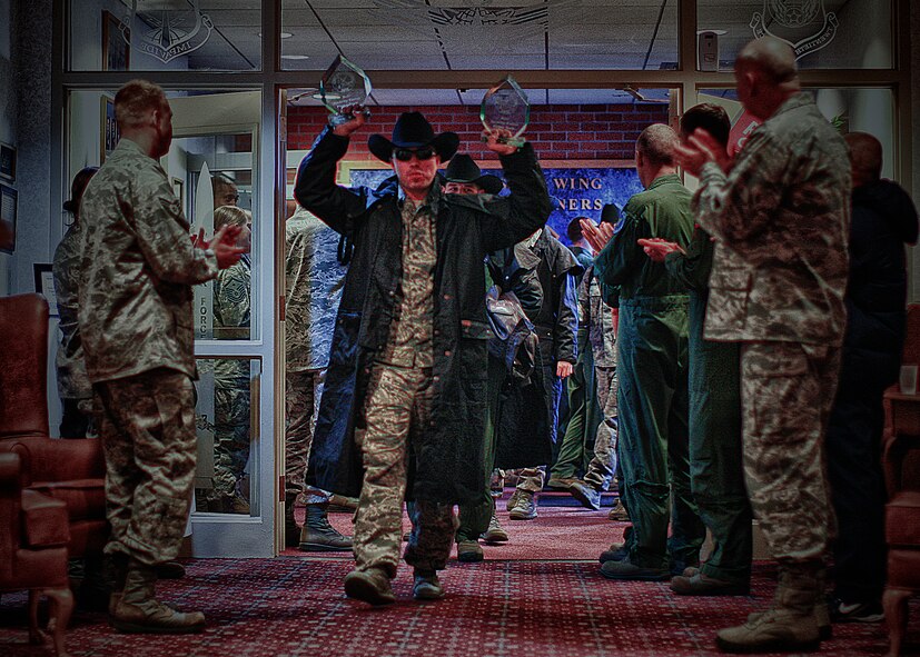 Tech. Sgt. Austin Wilson, 790th Missile Security Forces Squadron, holds up two awards won during the 2012 Global Strike Challenge as he enters the Trail's End Club Nov. 8 as Mighty Ninety members cheer in celebration of the Warren Wranglers' return from the score-posting Symposium held at Barksdale Air Force Base, La.