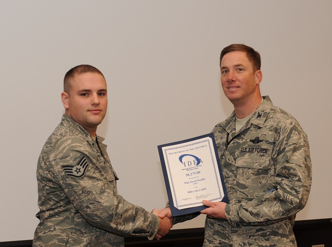 Staff Sgt. Jared Weddle, 2nd Maintenance Squadron communications navigations mission system craftsman, receives an award from Col. Alexis Mezynski, 2nd Bomb Wing vice commander, for an IDEA he had as a Senior Airman on Barksdale Air Force Base, La., Nov. 14. Weddle submitted an idea that would improve how a B-52H Stratofortress part is fixed, which saved manpower hours and shipping costs for the Air Force. The Air Force IDEA program is an incentive program that promotes process improvement and resource savings through ideas submitted by military and civilian employees. (U.S. Air Force photo/Airman 1st Class Benjamin Gonsier)(RELEASED)