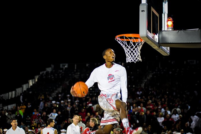 Service members from Joint Base Charleston watch from the stands as a member of the Ohio State men’s basketball team warms up before the start of the match between the Marquette University men’s basketball team during the 2nd Annual Carrier Classic team Nov. 9, 2012 in Charleston, S.C. The men's and women's basketball teams from Ohio State University, as well as the Notre Dame women's team and Marquette University men's team were scheduled to play. The men’s game between Marquette University and Ohio State was canceled due to moisture on the court. (U.S. Air Force photo/ Senior Airman Dennis Sloan)