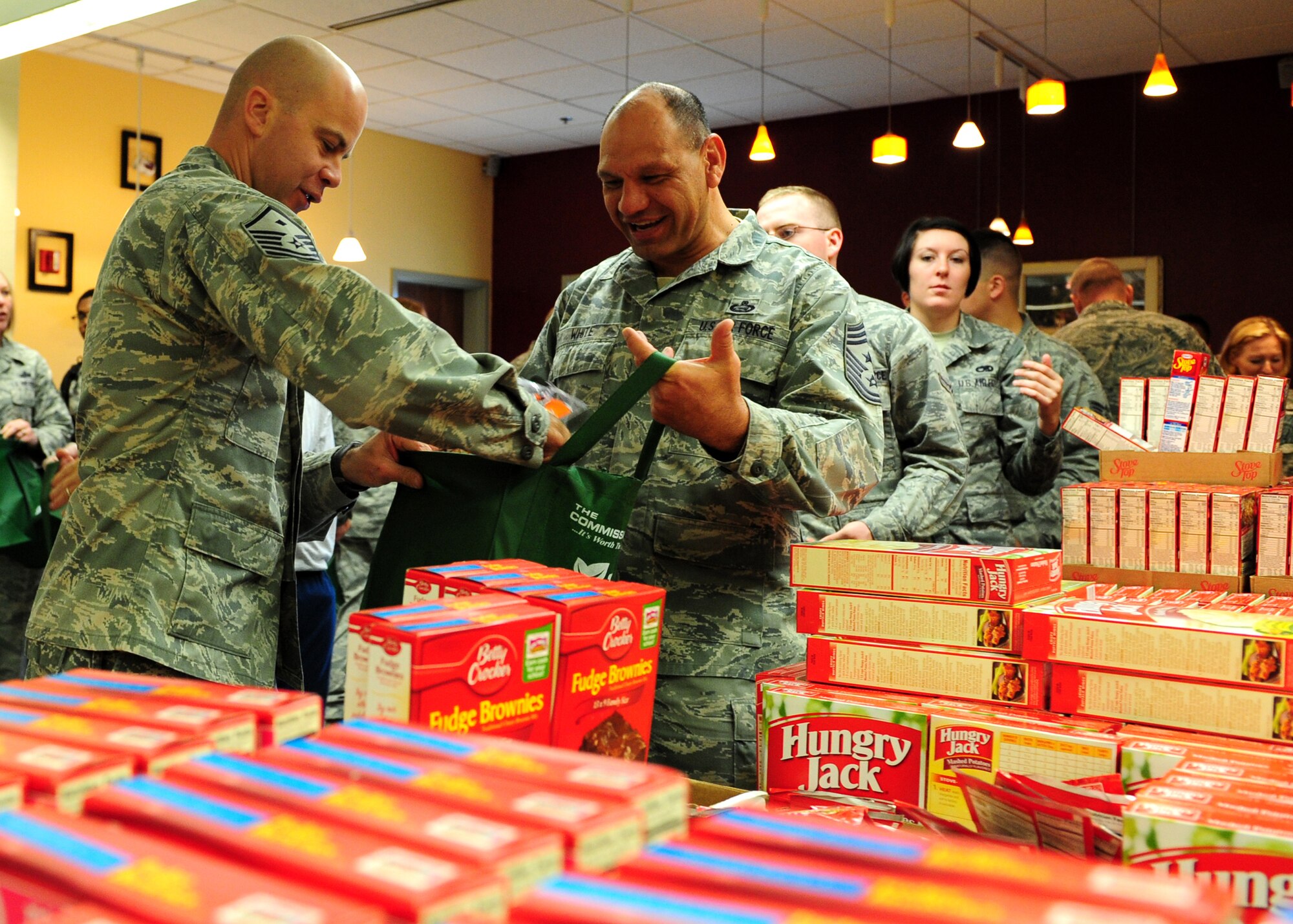 Master Sgt. Jason Davis, 489th Reconnaissance Squadron first sergeant, packs food in a bag held by Chief Master Sgt. Robert White, 9th Reconnaissance Wing command chief, Nov. 16, 2012, at Beale Air Force Base, Calif. The food will be delivered to Airmen for Thanksgiving, kicking off the holiday season for Operation Warm Heart, a program supporting Airmen and their families during times of need. (U.S. Air Force photo by Senior Airman Shawn Nickel/Released)