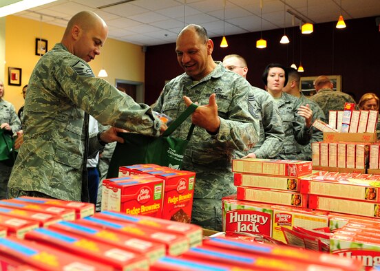 Master Sgt. Jason Davis, 489th Reconnaissance Squadron first sergeant, packs food in a bag held by Chief Master Sgt. Robert White, 9th Reconnaissance Wing command chief, Nov. 16, 2012, at Beale Air Force Base, Calif. The food will be delivered to Airmen for Thanksgiving, kicking off the holiday season for Operation Warm Heart, a program supporting Airmen and their families during times of need. (U.S. Air Force photo by Senior Airman Shawn Nickel/Released)