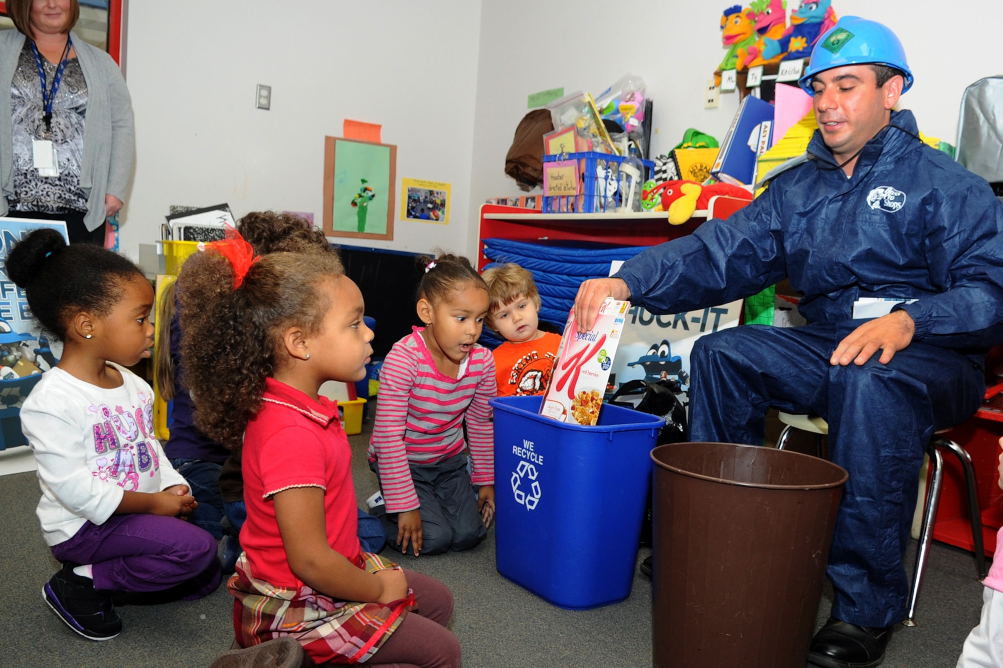 Michael Mallozzi, right, 633rd Civil Engineering Squadron pollution preventative manager, demonstrates proper recycling with children from the Russ Child Development Center during an America Recycles Day event at Langley Air Force Base, Va., Nov. 15, 2012. Mallozzi taught the children about various recyclable items, including cereal boxes, aluminum cans, newspapers and printer paper. (U.S. Air Force photo by Senior Airman Racheal E. Watson/Released)