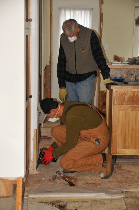 Dan Marren (foreground) and homeowner Ed Chase (standing) remove flooring following Super Storm Sandy that flooded the first floor of Chase’s home.  The storm brought heavy rain and wind and resulted in thousands of power outages along the East Coast.