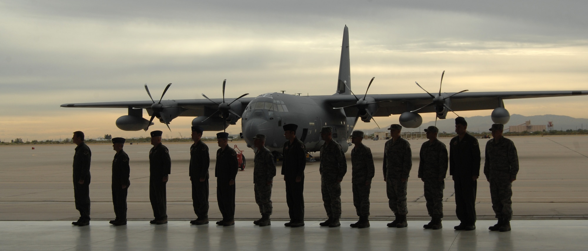 The crew of the HC-130J stands at attention in front of their plane on Davis-Monthan Air Force Base, Ariz., Nov. 15. The J model has new features including chaff and flare dispensers, threat detection capabilities and the ability to refuel inflight. (U.S. Air Force photo by Senior Airman Michael Washburn/Released)