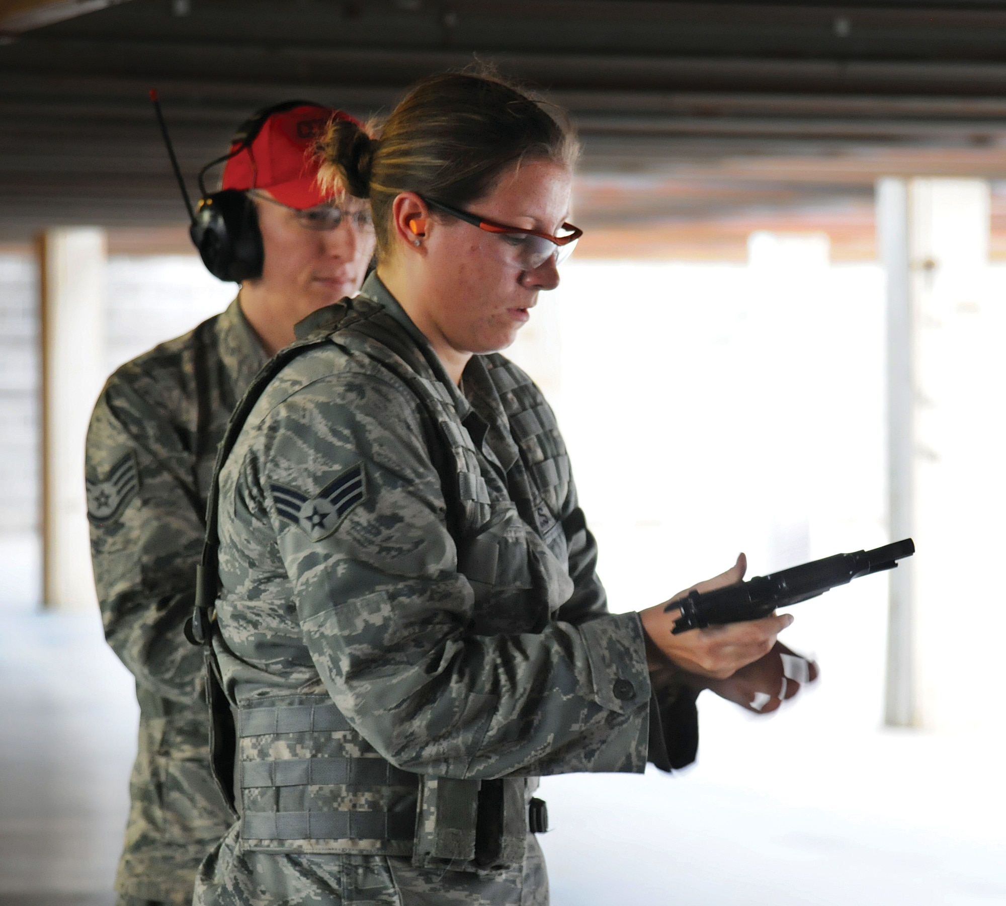 Senior Airman Jocelyn Lord, 97th Security Forces Squadron, Altus AFB, reloads under pressure during a Combat Pistol competition at the Tinker Combat Arms firing range Nov. 10.  Altus hit the mark for the pistol competition, earning the five-person team the win in that event. Watching each competitor is 72nd SFS Combat Arms Staff Sgt. Matthew Leake.  (Air Force photo by Margo Wright)