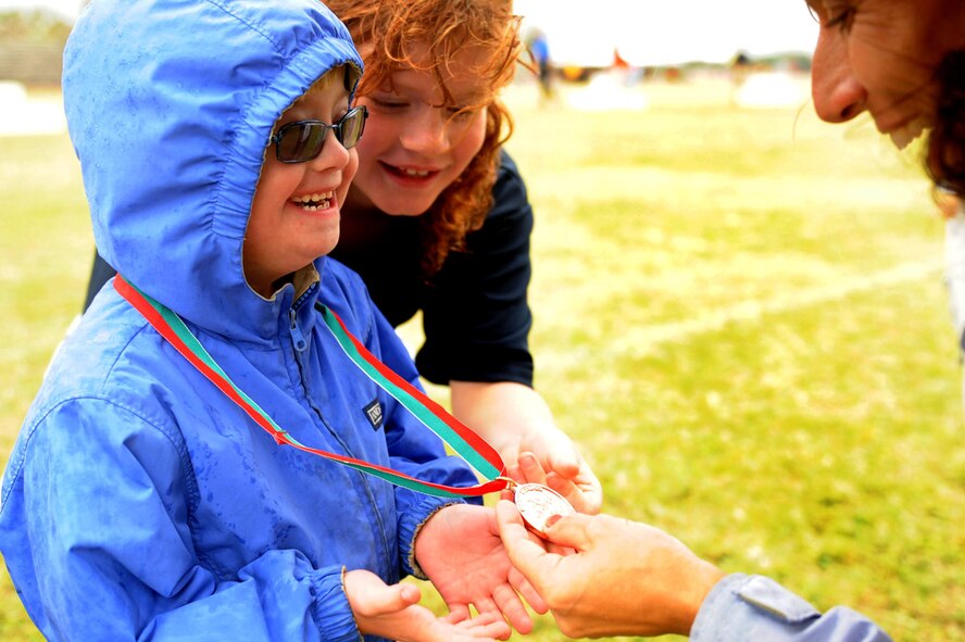 Marlee McDaniel, daughter of U.S. Air Force Col. Brain McDaniel, 18th Wing vice commander, shows off her medal to her sister and Hugger after she participated in the 30 meter dash a the the Kadena Special Olympics on Kadena Air Base, Japan, Nov. 17, 2012. Marlee is participating in KSO for the first time this year and also participated in the 30 meter dash, and softball throw. (U.S. Air Force photo/Airman 1st Class Brooke P. Beers)