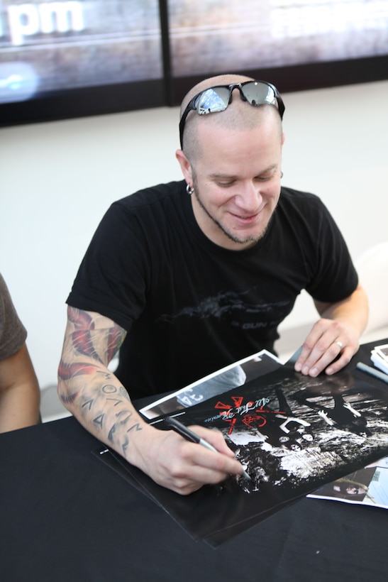 Phil Labonte, lead vocalist of heavy metal band All That Remains, signs a poster for a military fan while visiting service members aboard Marine Corps Base Camp Lejeune recently. Labonte was in the Marine Corps briefly but was medically separated.  