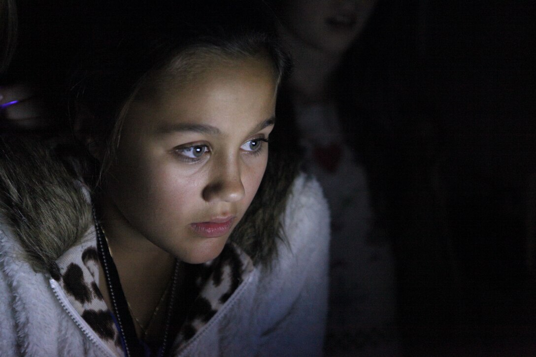 A girl listens intently to the puck, a device that speaks words based on environmental readings at the North Caroline USO in Jacksonville Nov. 14. The girls where there investigating with members of a local radio station, the South East Paranormal Investigation Association, and Bruce Tango, a paranormal investigator who frequently guest stars on "Ghost Hunters," a TV show on SyFy network.  