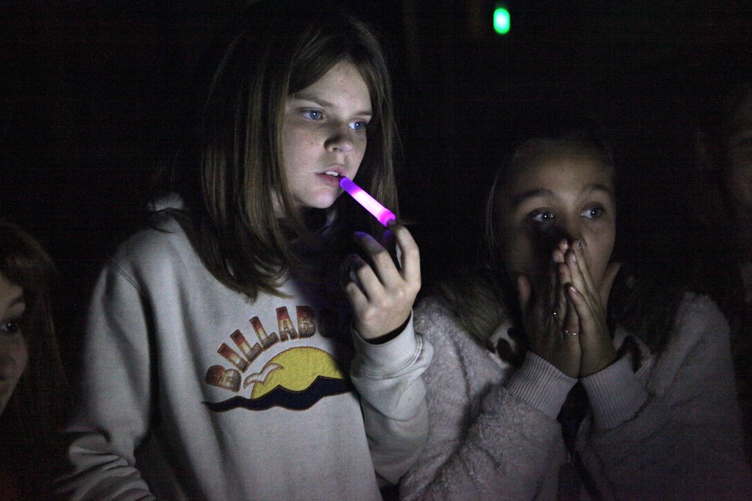 Two girls listen intently to the puck, a device that speaks words based on environmental readings at the North Caroline USO in Jacksonville Nov. 14. The girls where there investigating with members of a local radio station, the South East Paranormal Investigation Association, and Bruce Tango, a paranormal investigator who frequently guest stars on "Ghost Hunters," a TV show on SyFy network.  