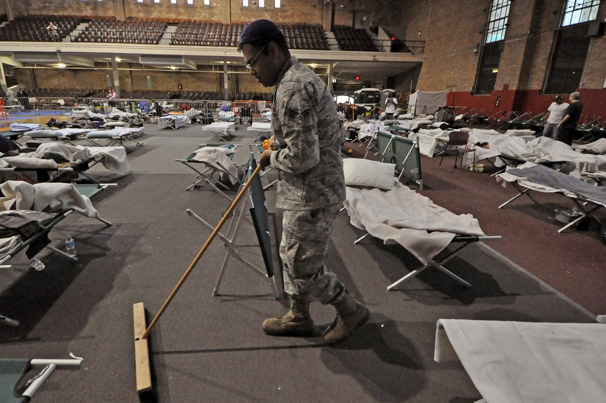 Senior Airman Mohammed Siddiqui, 108th Wing, sweeps the sleeping area for displaced residents at Jersey City, Nov. 7. The New Jersey National Guard is providing sheltering for displaced Jersey City residents at the Jersey City armory. (U.S. Air Force photo by Staff Sgt. Armando Vasquez/Released)