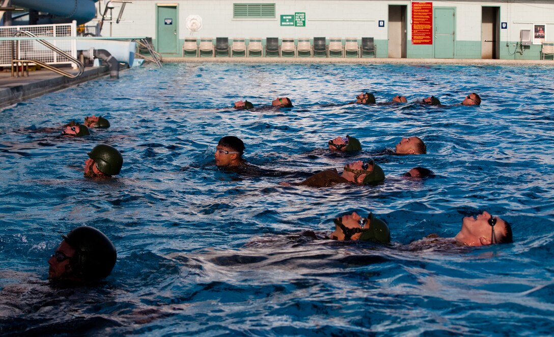 Marines conduct a gear rescue evolution during a Marine Corps Instructor of Water Survival course at the base pool on Marine Corps Base Hawaii, Monday. Considered one of the toughest courses in the Marine Corps, both physically and mentally, the course teaches students to become water survival instructors. As an instructor, Marines learn to instruct and certify students in water survival. The course demands that students become proficient in various skills, such as swimming strokes, cardiopulmonary resuscitation and rescue techniques in the event of an emergency situation.