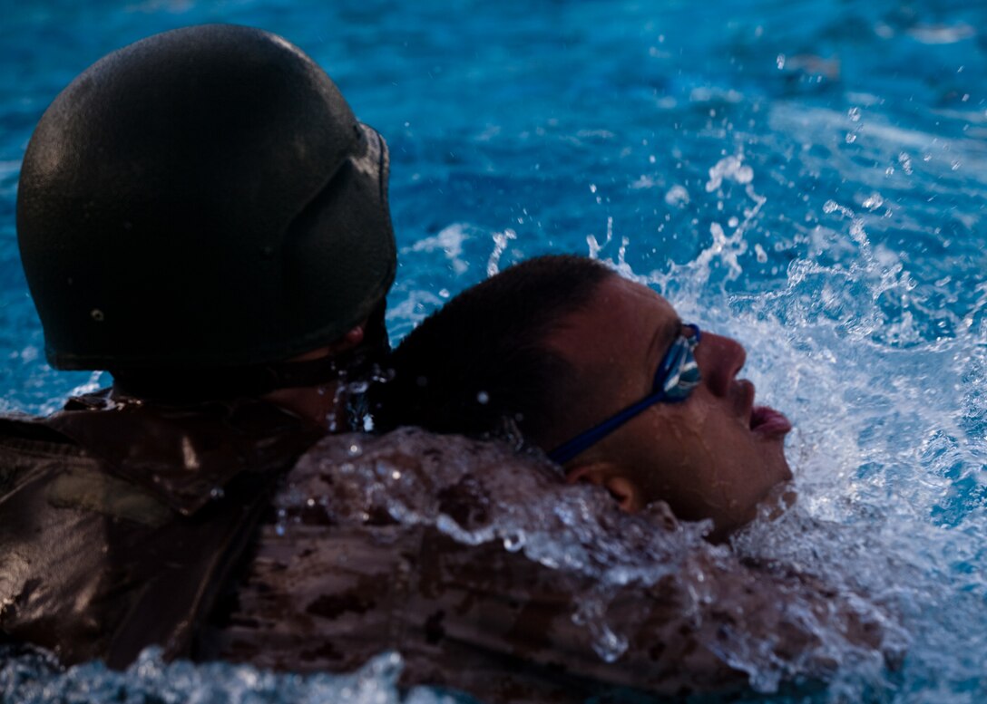 A victim in combat gear grabs hold of 1st Lt. Clark Petersen, a field artillery officer with 1st Battalion, 12th Marine Regiment, and drags him underwater during a gear rescue evolution of a Marine Corps Instructor of Water Survival course at the base pool on Marine Corps Base Hawaii, Monday.