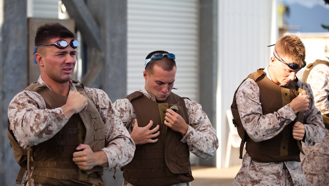Marines from different units on Marine Corps Base Hawaii don combat gear before entering the base pool during a Marine Corps Instructor of Water Survival course, Monday.