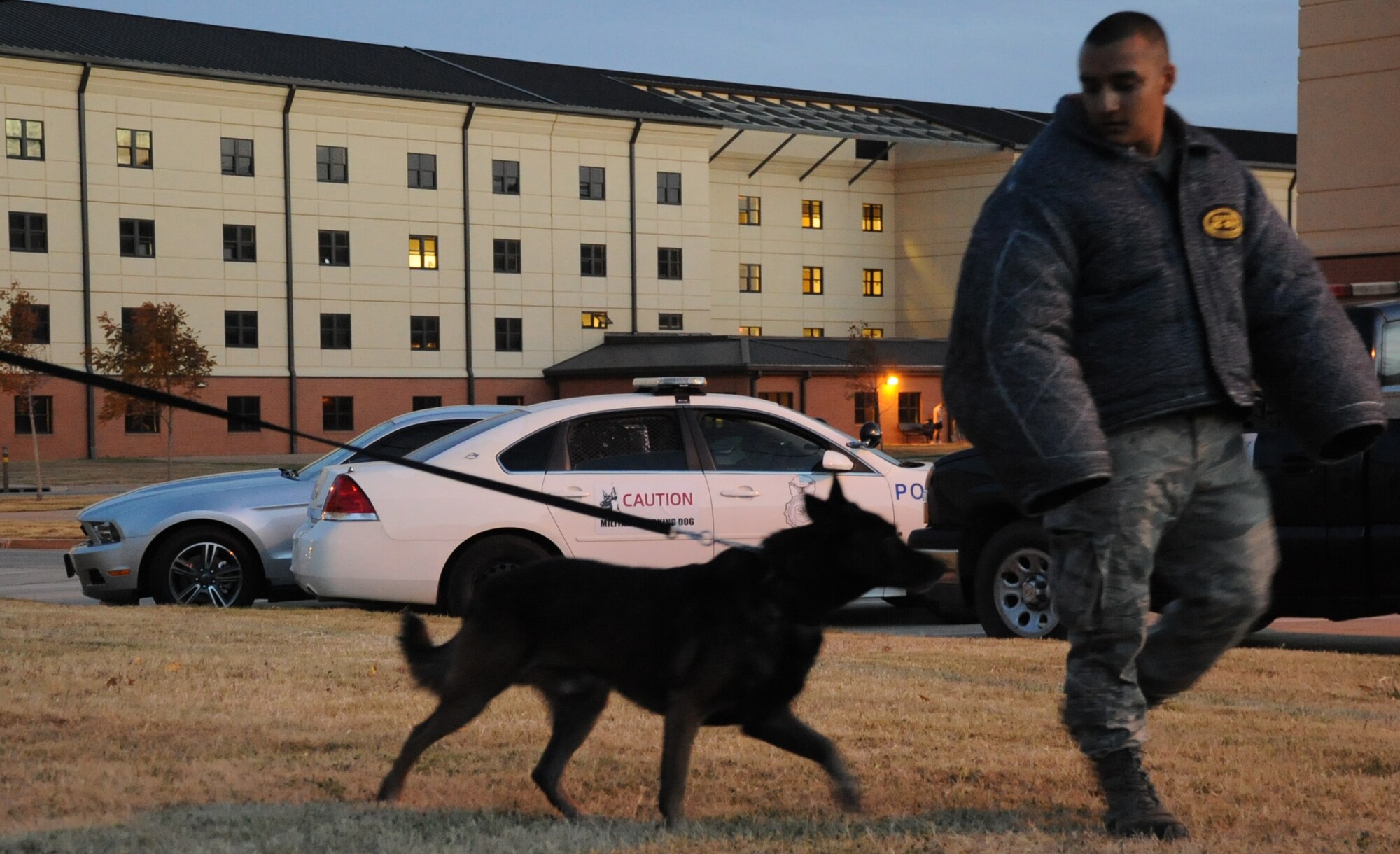 Senior Airman Julian Becerra uses Duck a military working dog to demonstrate how the dogs escort suspects during a demonstration at the Airman & Family Readiness Center on Nov. 19.  (U.S. Air Force Photo/Kimberly Parker)