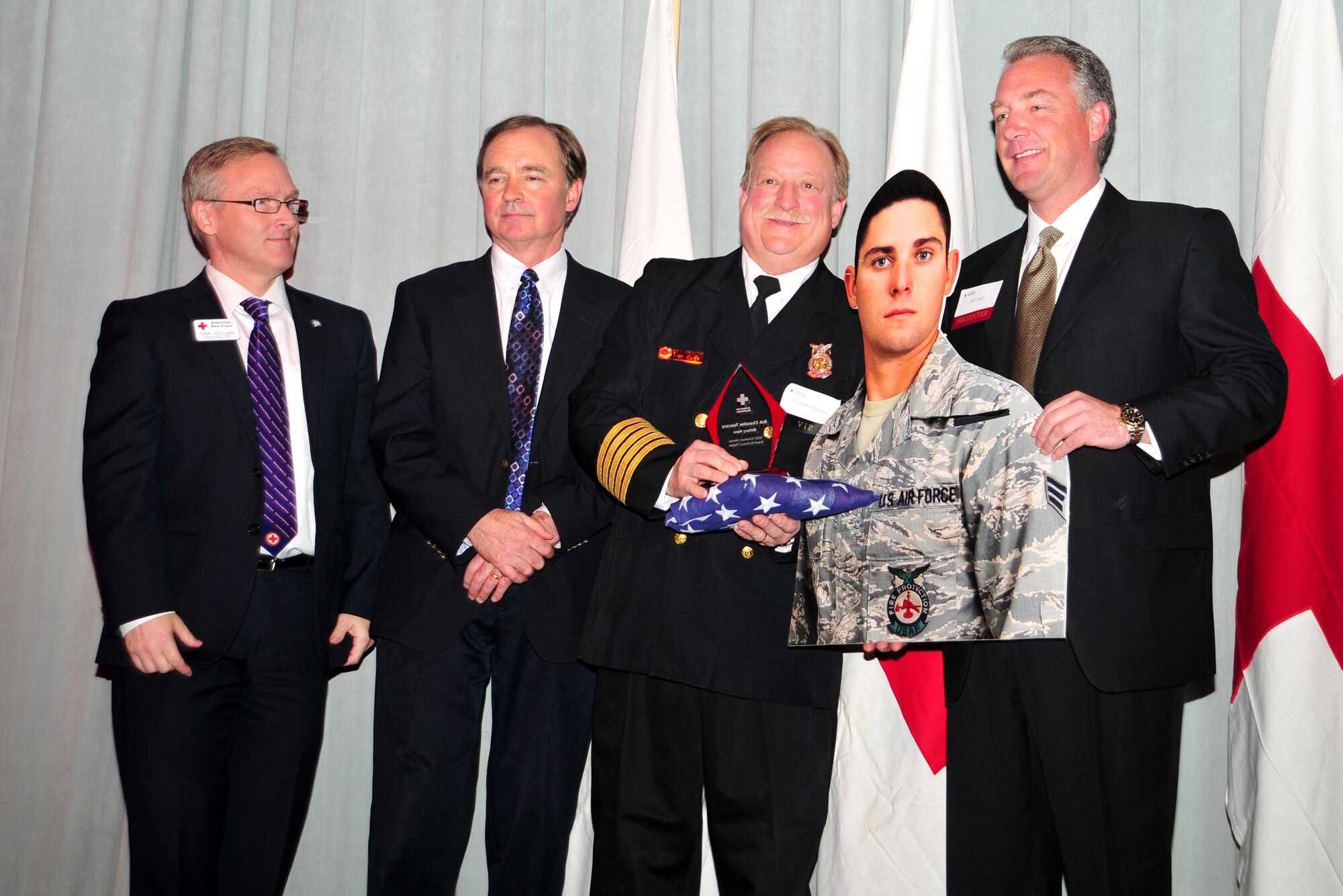 Fire Chief Bill Nowlin accepts the Military Hero award on behalf of Senior Airman Chandler Tuscany at the Hometown Heroes luncheon, Nov. 15, 2012. The American Red Cross awards individuals who have made a positive impact on the lives of others, whether through a life-saving action or tireless effort to benefit the community. Tuscany is with the 92nd Civil Engineer Squadron. (U.S. Air Force photo by Airman 1st Class Taylor Curry)