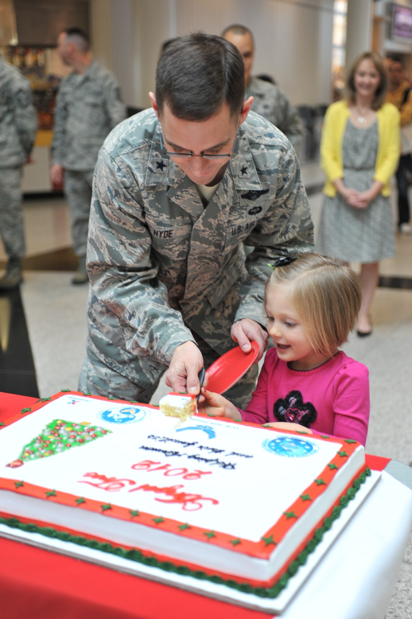 Brig. Gen. C.K. Hyde, 86th Airlift Wing commander and Audrey McNabb, 3 year old daughter of Tech. Sgt. Jason McNabb, 435th Contingency Response Group, cut a cake kicking off the 2012 Angel Tree Program on Ramstein Air Base, Germany, Nov. 16, 2012. The Angel Tree Program helps provide financial relief which helps in the purchase of gifts for children during the holiday season. (U.S. Air Force photo/Senior Airman Caitlin O’Neil-McKeown)