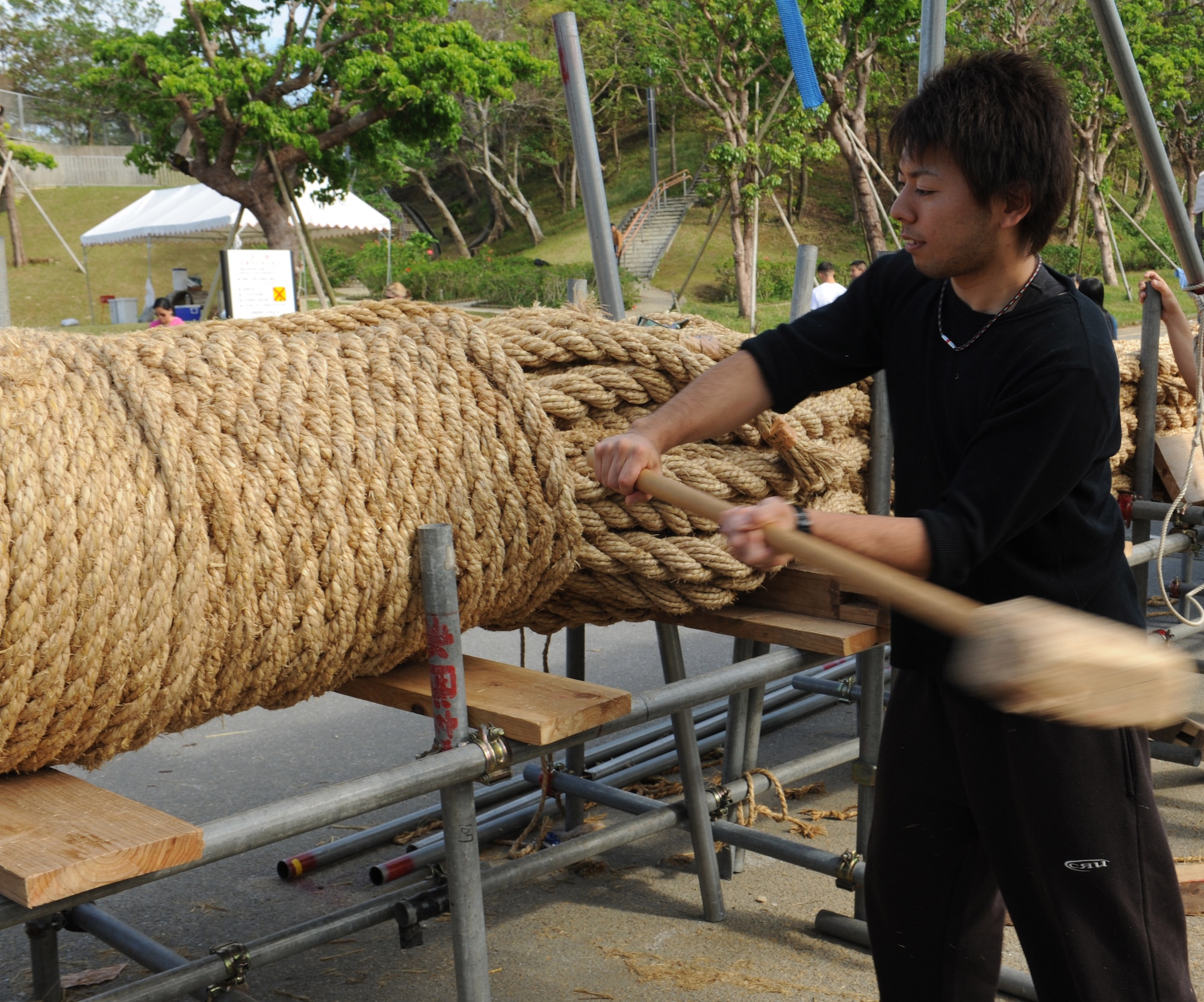 Yuki Isa, a local Okinawan community member, hammers a piece of rope into the International Tug-of-War rope in Okinawa City, Japan, Nov. 18, 2012. Individual pieces of rope are stacked, wrapped and then pounded into place to create the giant rope used for the International Tug-of-War. (U.S. Air Force photo/Airman 1st Class Malia Jenkins)