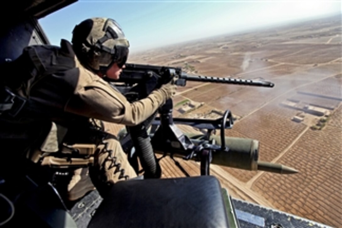 U.S. Marine Corps Cpl. Jeffery L. Allen fires a gun from his helicopter over the Helmand province of Afghanistan, on Nov. 8, 2012.  Allen, a crew chief with Marine Light Attack Helicopter Squadron 469, and the rest of the crew provided close air support to members with the International Security Assistance Force.  