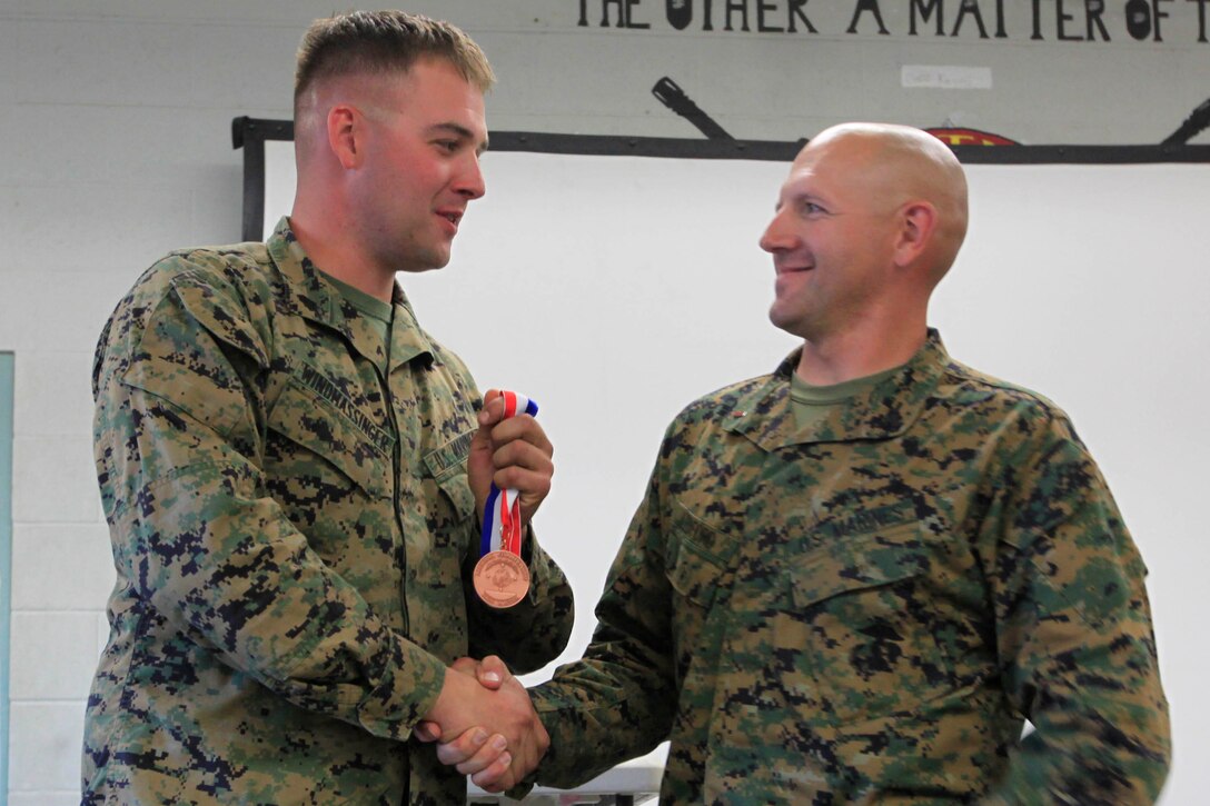 Sgt. Mark D. Windmassinger (left), 27, the noncommissioned officer in charge of the Marine Corps Base Camp Pendleton Shooting Team, receives a 1st place medal for being the Top High-Master Shooter in the service rifle category from Chief Warrant Officer (Gunner) Duane S. Ledford, range officer in charge and coach for the 29 Palms shooting team, after the National Rifle Association Match at the known-distance range here Nov. 17.