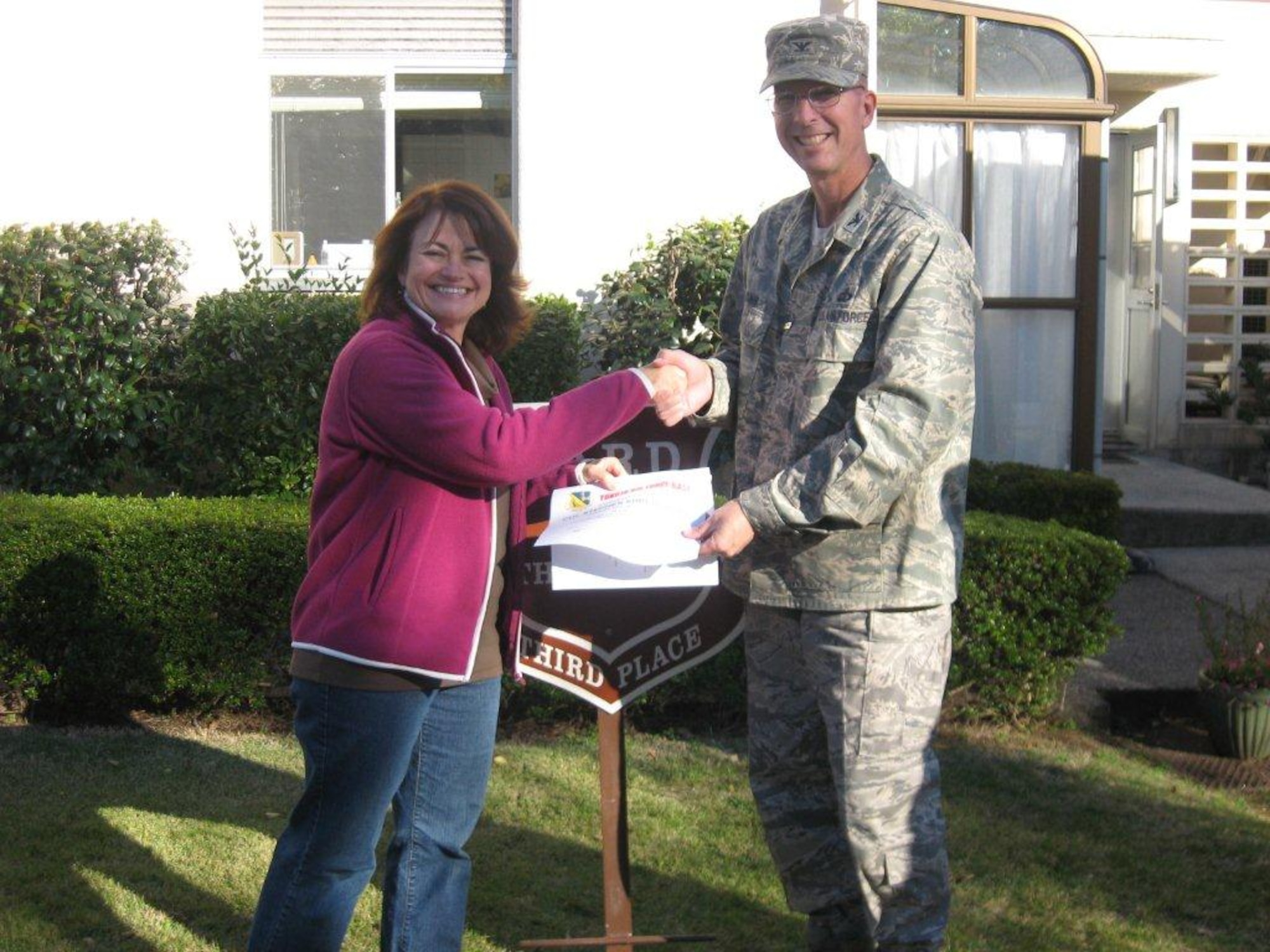 YOKOTA AIR BASE, Japan -- Col. Edward Brown, right, 374th Mission Support Group commander, presents a certificate to Lori Shrewsburry, wife of Col. Stephen Shrewsburry, 5th Air Force judge advocate, congratulating her on winning 3rd place in the new Yard of the Month program at Yokota Air Base, Japan. (Courtesy photo from the 374th Civil Engineer Squadron)