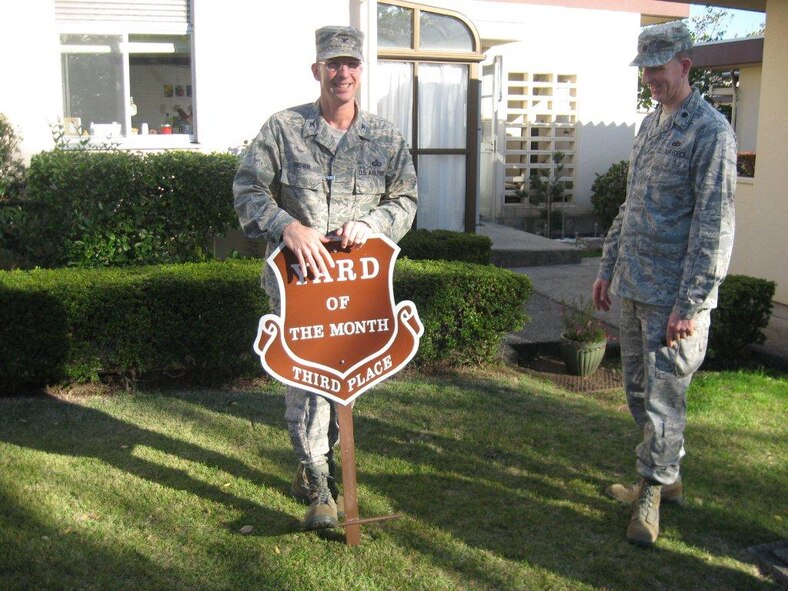 YOKOTA AIR BASE, Japan -- Col. Edward Brown, left, 374th Mission Support Group commander, sets up a sign showing that a yard won third place in the new Yard of the Month program at Yokota Air Base, Japan. (Courtesy photo from the 374th Civil Engineer Squadron)