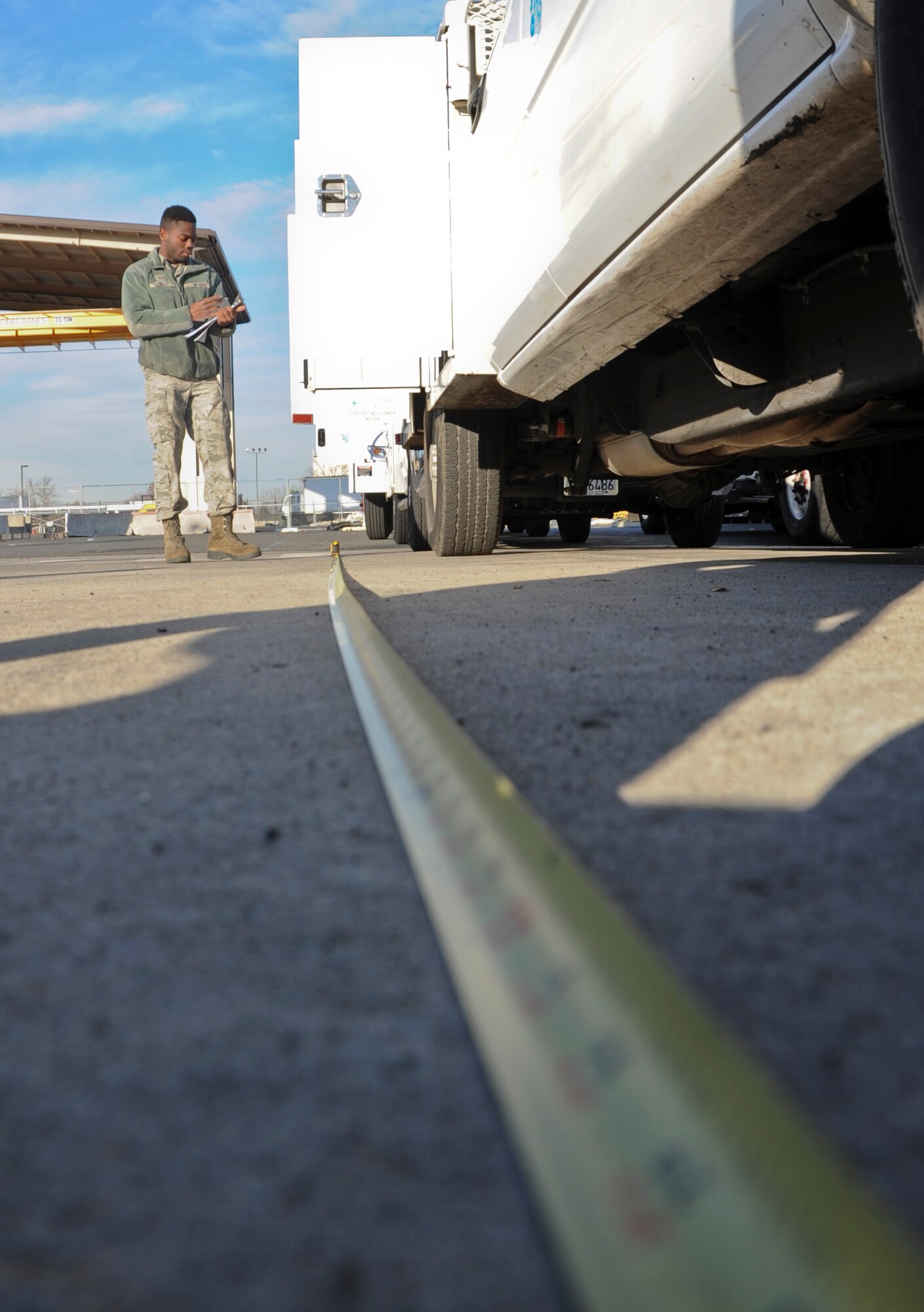 Senior Airman Marquis Cole, 305th Aerial Port Squadron aerial transportation specialist, uses a tape measure to process a power line truck Nov. 16, 2012, during the cargo in-check at Joint Base McGuire-Dix-Lakehurst, N.J. Cole and his fellow aerial transportation specialists measured the vehicle’s length, width and height, which will be used by load planners to facilitate cargo manifests. The utility and line trucks were flown back to California after they were used in hurricane-relief efforts. (U.S. Air Force photo by Staff Sgt. David Carbajal/Released)
