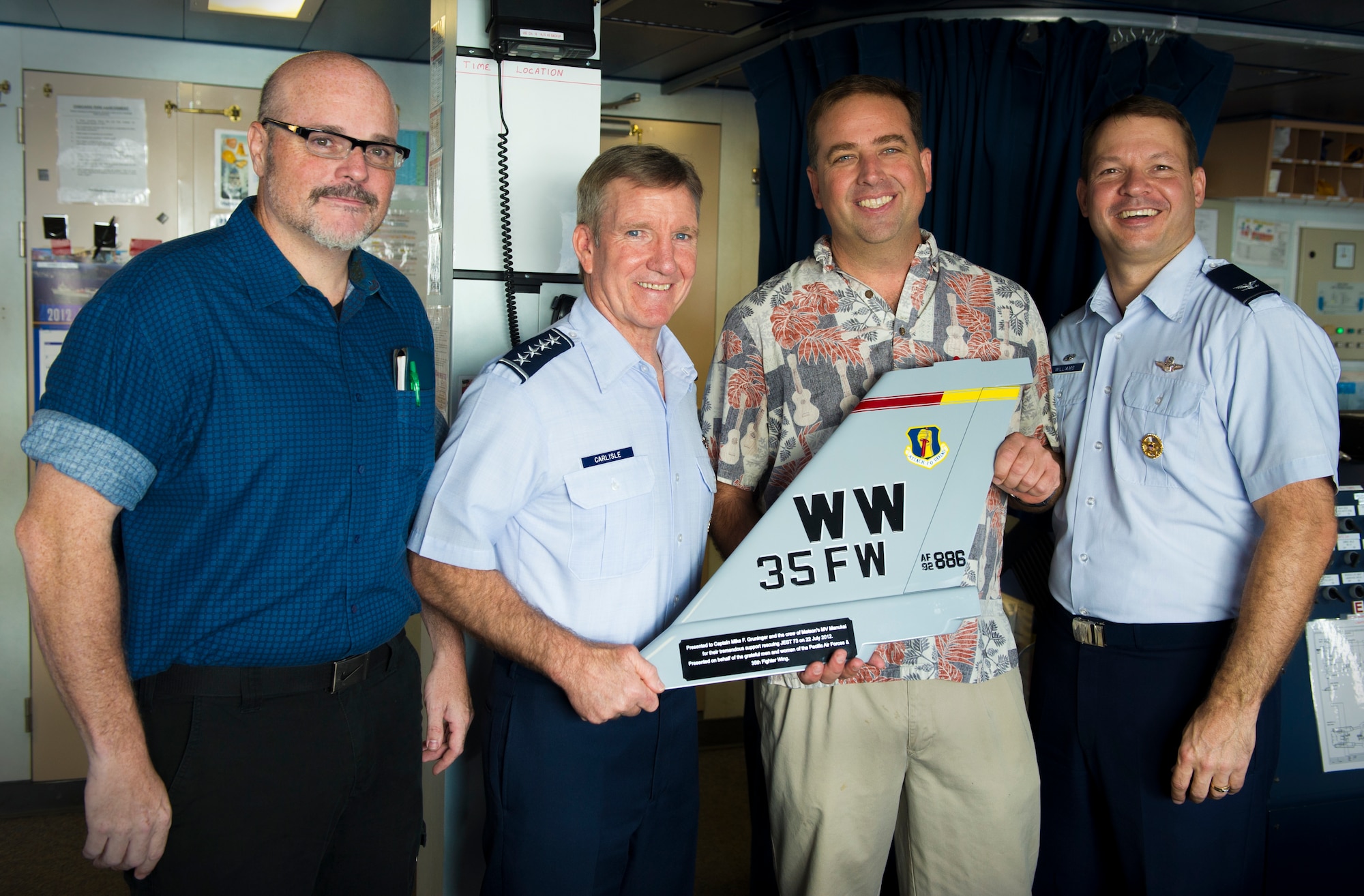 Dan Massoni, chief engineer of the MV Manukai, a Matson commercial cargo ship; Gen. Herbert J. “Hawk” Carlisle, Pacific Air Forces commander; ship Captain Mike F. Gruninger; and Col. Stephen Williams, 35th Fighter Wing commander, pose for a group photo aboard the Manukai in Honolulu, Hawaii, Nov. 19, 2012. Carlisle presented Gruninger with a tail flash plaque on behalf of the men and women of PACAF and the 35th Fighter Wing. The plaque is dedicated to the crew of the ship for rescuing a U.S. Air Force F-16 Fighting Falcon pilot, who had to eject from his aircraft into the North Pacific in July. (U.S. Air Force photo/Tech. Sgt. Aries Early)