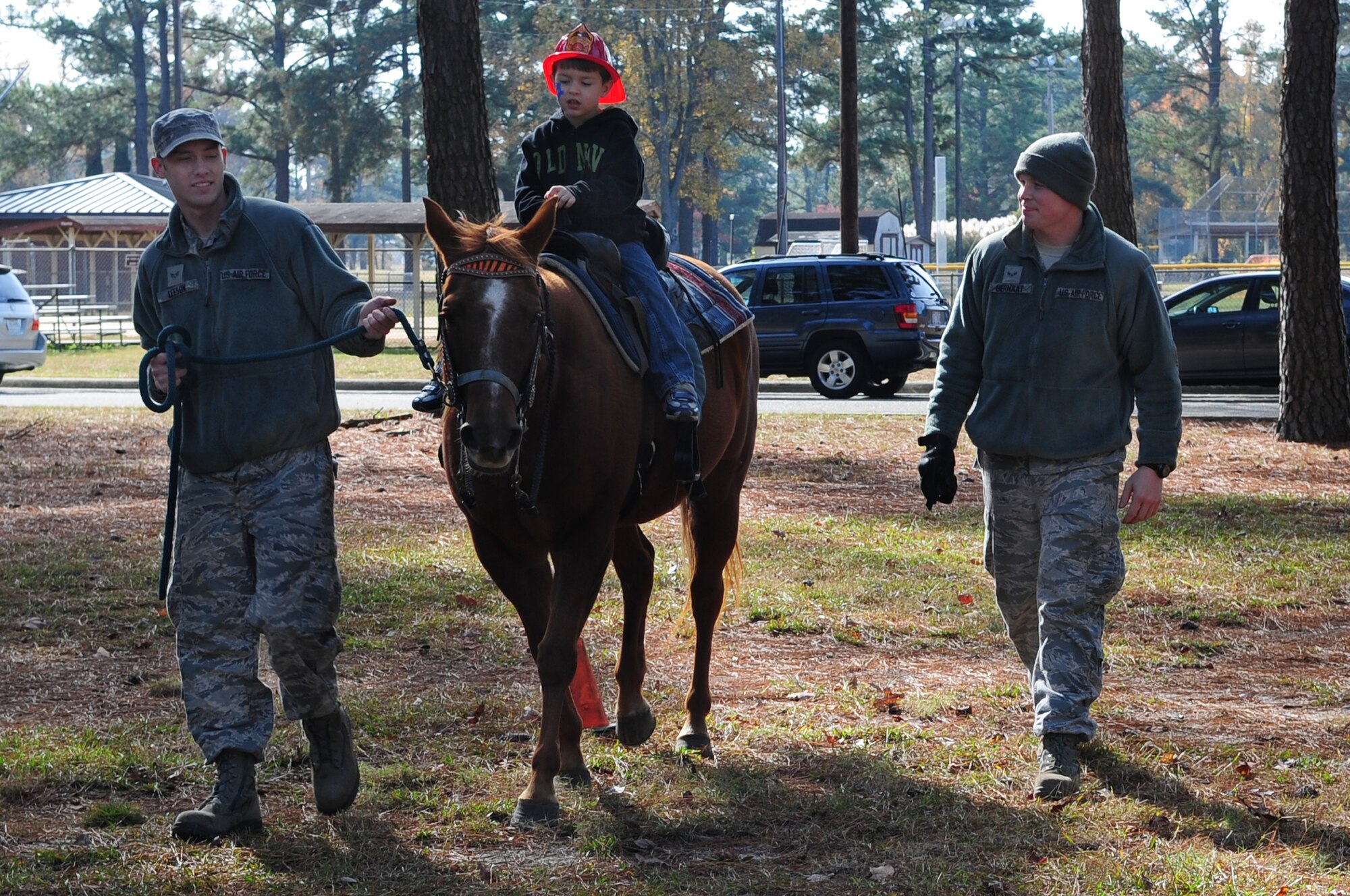 U.S. Air Force Senior Airman Scottie Leeson and Airman 1st Class Matthew Gernaat, 4th Civil Engineer Squadron fire fighters, walk alongside Gavin Rands, 5, as he rides a horse during the Month of the Military Family Block Party on Seymour Johnson Air Force Base, N.C., Nov. 17, 2012. Gavin is the son of retired U.S. Air Force master sergeant Keith Rands. (U.S. Air Force photo/Airman 1st Class Aubrey White/Released)