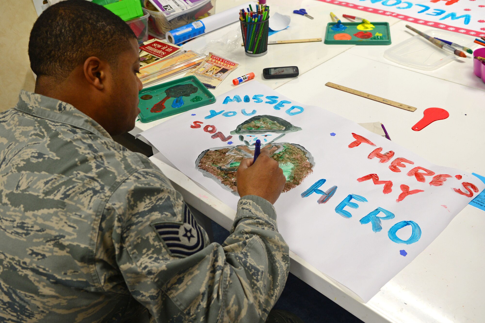 A parent paints a welcome home sign for their child during the deployment camp at Aviano Air Base, Italy, Nov. 17. The base simulated a deployment for children with military family members to give them an opportunity to see what the parents go through. (U.S. Air Force photo/Airman 1st Class Matthew Lotz) 