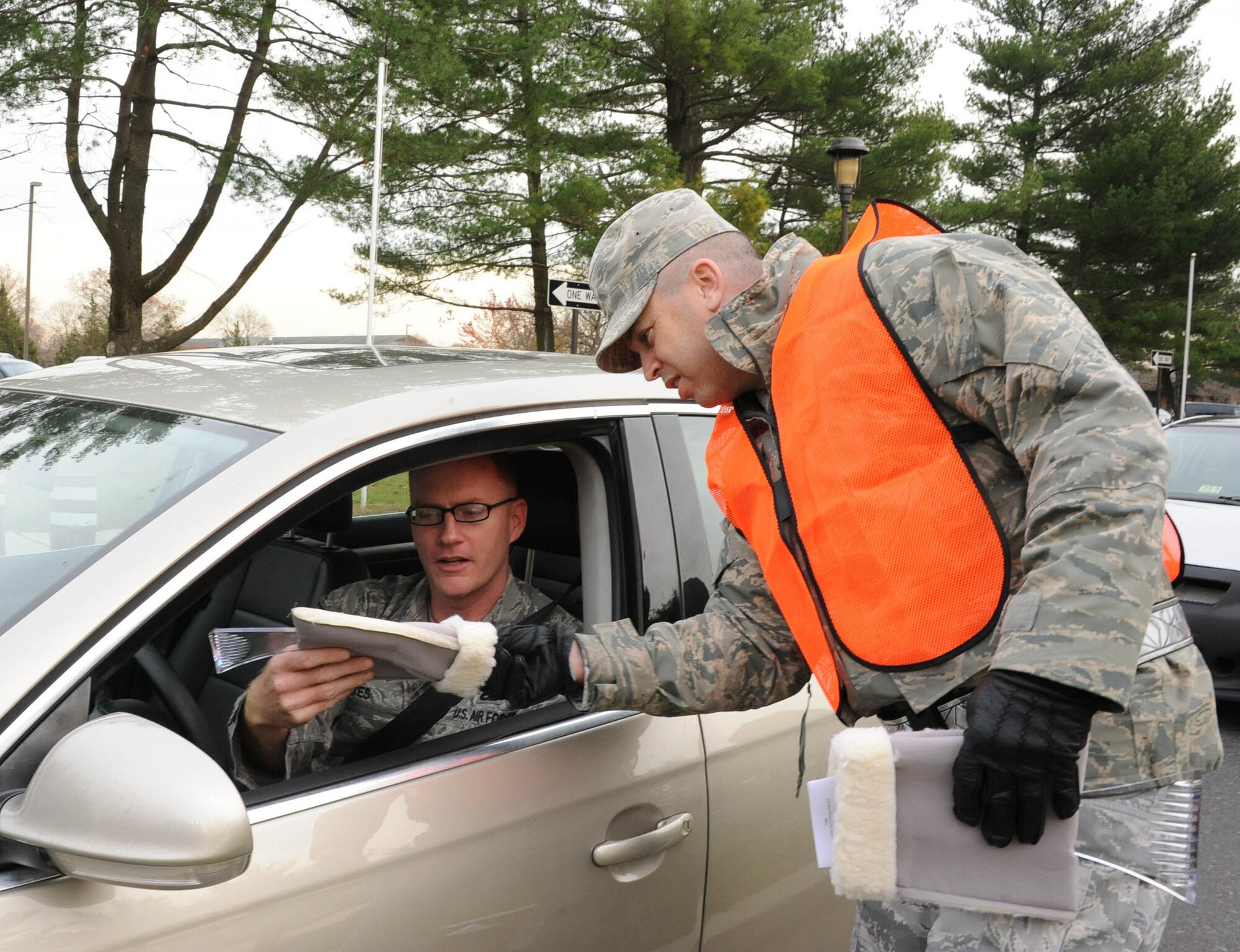 Maj. Andrew Griffin, 605th Aircraft Maintanance Squadron commander, hands out ice scrapers at Nov. 21, 2012, at Joint Base McGuire-Dix-Lakehurst, N.J. Leaders are greeting people at the gate to pass out holiday safety information. (U.S. Air Force photo by Airman Sean Crowe/Released)