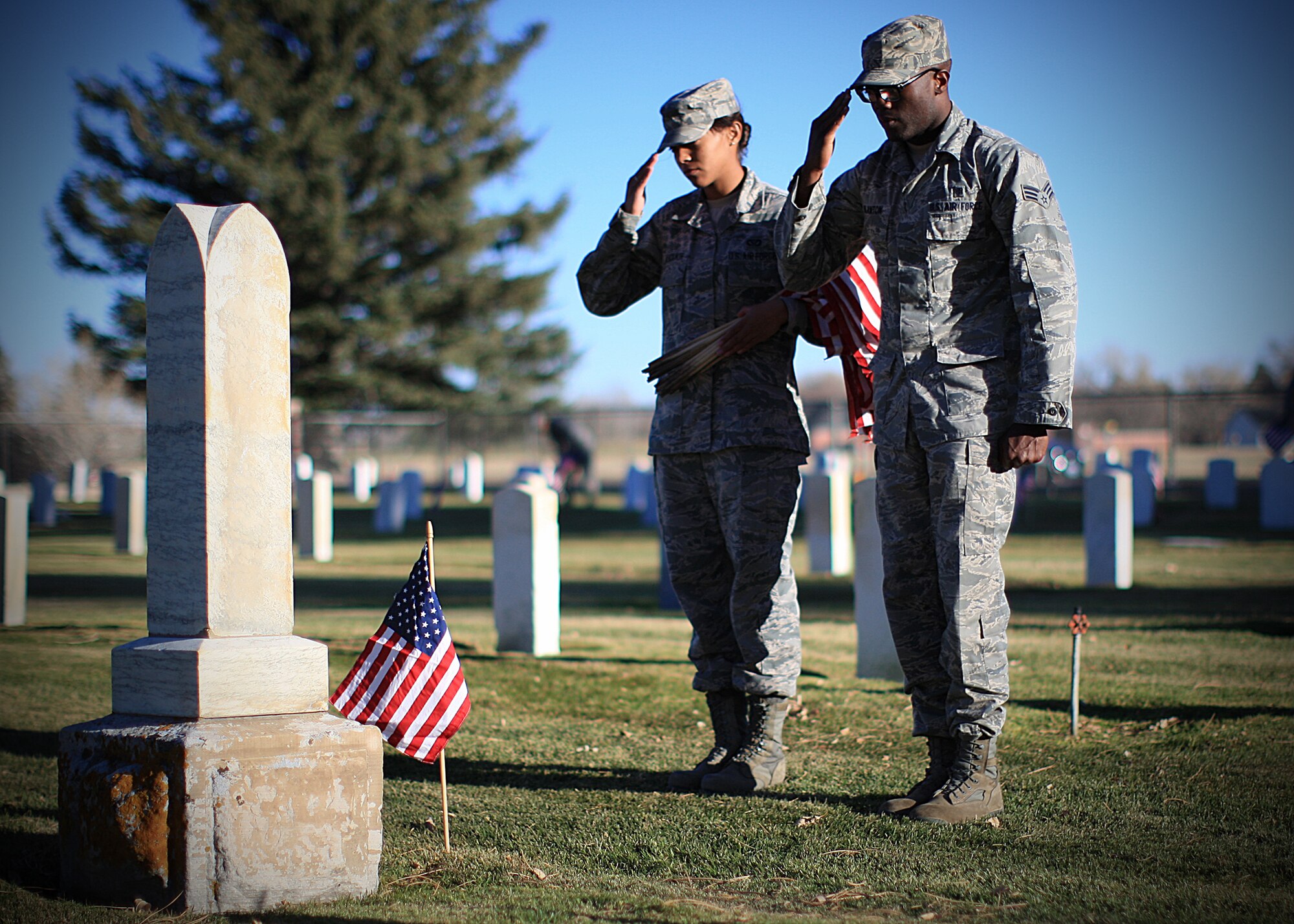 Senior Airman Brandon Blanton, 90th Medical Operations Squadron, and Airman 1st Class Danae Blackmon, 90th Civil Engineer Squadron, both members of the 90th Missile Wing Honor Guard, salute the U.S. flag during the Veterans Day flag-laying ceremony at the F. E. Warren Base Cemetery Nov. 9. (U.S. Air Force photo by Matt Bilden)