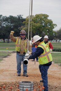 Steven Knight(left) gives directions to a crane operator, while Ricardo Muniz and Bruce Real position the POW/MIA flag pole for installation Nov. 13 at Joint Base San Antonio-Randolph Airmen's Heritage Park. (U.S. Air Force photo by Don Lindsey)