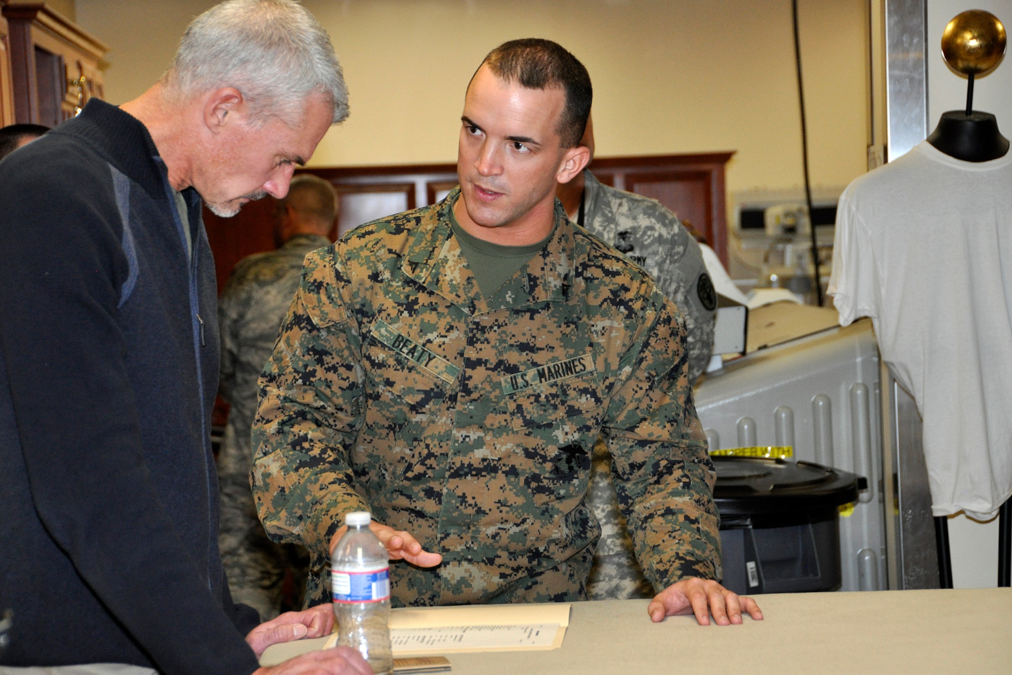 Retired Marine Lt. Col. Michael R. Strobl, whose diary was the basis for the 2009 HBO film "Taking Chance," listens while Marine Lance Cpl. Landon Beaty, Air Force Mortuary Affairs Operations Marine Corps Liason, explains the tasks involved in preparing a uniform for a fallen Marine. Strobl visited the Port Mortuary in remembrance of his role in escorting Pfc. Chance Phelps remains home for burial. Phelps was killed in action in the Iraq war April 9, 2004. (U.S. Air Force photo/Master Sgt. Cherie McNeill)