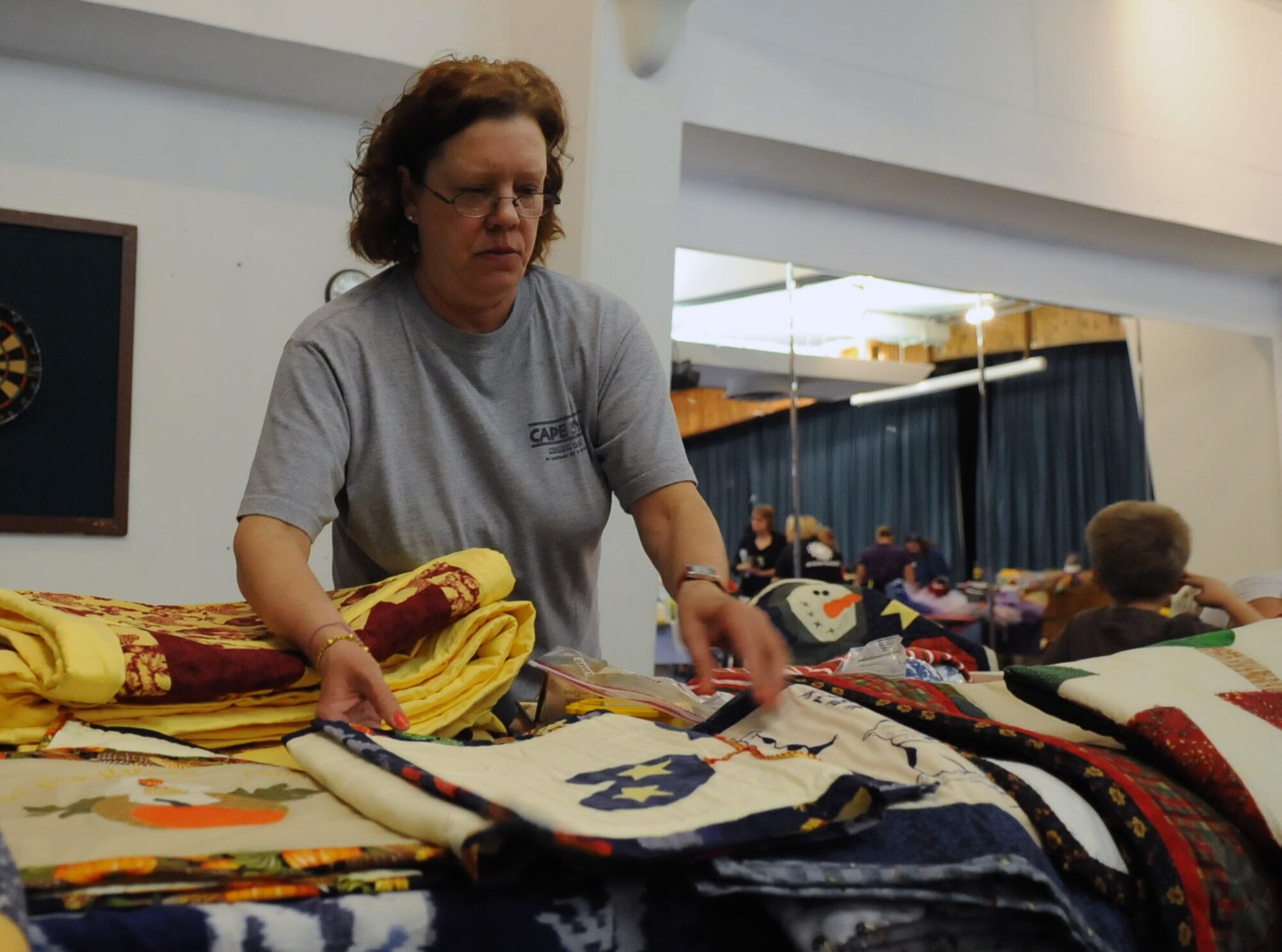 Sharon Proctor, Airman and Family Readiness Center community readiness consultant, arranges her quilts at the community center's holiday bazaar Nov. 17, 2012 at Incirlik Air Base, Turkey. Incirlik members visited the bazaar to see what other members of the community had to offer. (U.S. Air Force photo by Senior Airman Daniel Phelps/Released)
