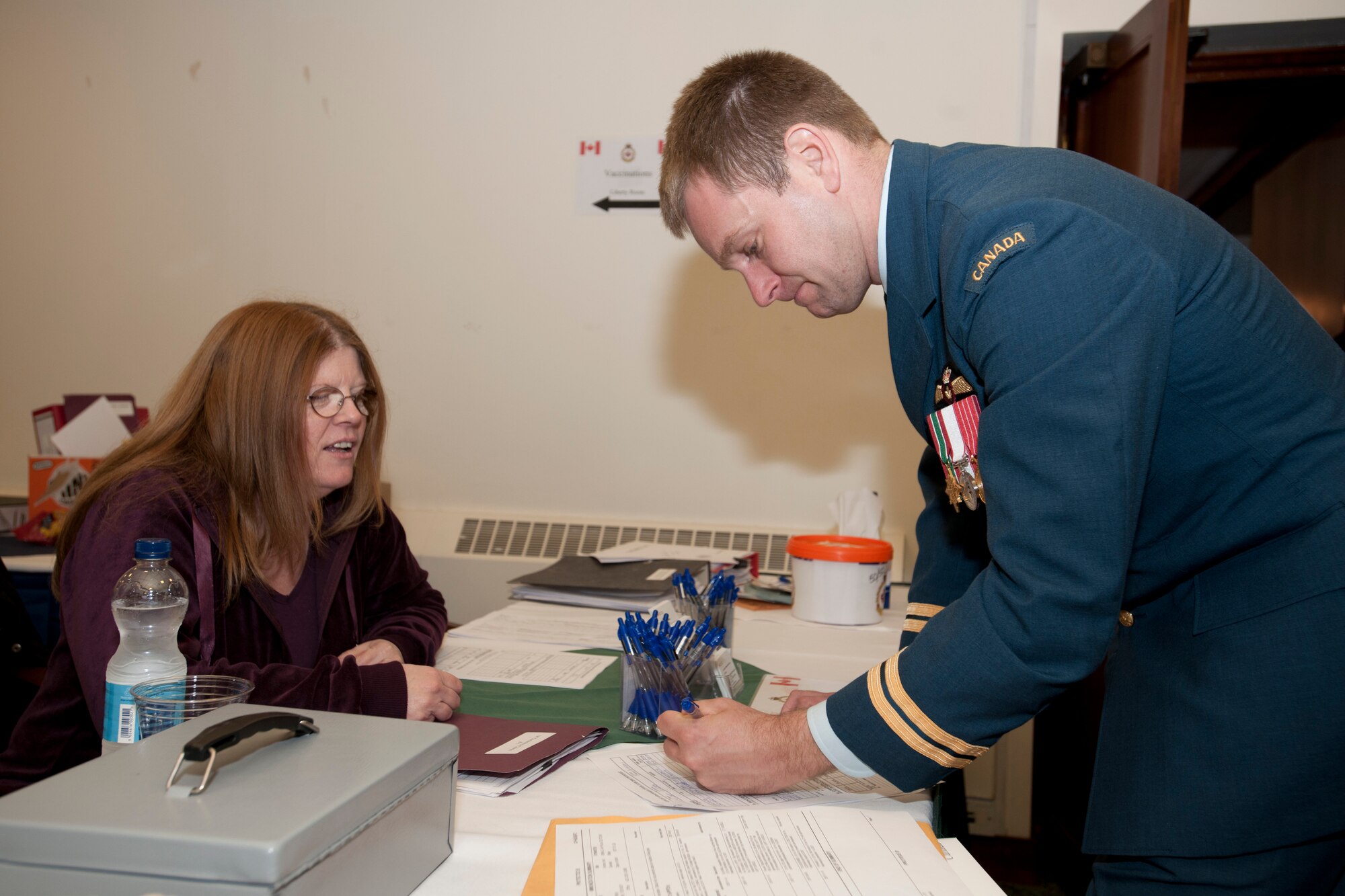 ROYAL AIR FORCE LAKENHEATH, England - Donna Seaward, Canadian Forces Support Unit education clerk, helps Royal Canadian Air Force Capt. Andrew Webb, RCAF pilot, fill out a registration form at the Canadian Forces U.K. Conference at Eagle's Landing Nov. 20, 2012. The CFSU hosted the conference, which provided an opportunity for officers and NCOs serving in the U.K. to interact with local government agencies, national government agencies and local support agencies. (U.S. Air Force photo by Staff Sgt. Stephen Linch)