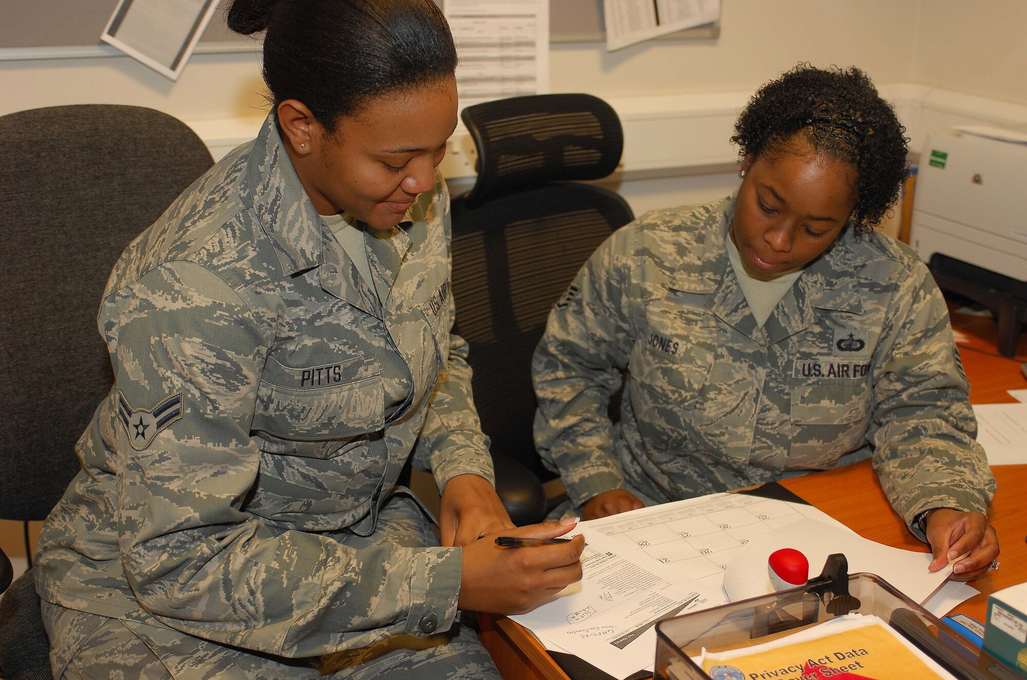 ROYAL AIR FORCE LAKENHEATH, England - Staff Sgt. Crystal Jones, 48th Comptroller Squadron NCO in charge of customer service (right), goes over paperwork with Airman 1st Class Madison Pitts, 48th CPTS customer service technician (left), Nov. 20, 2012. Jones was nominated for a Liberty Spotlight because she displays the core value of "Service Before Self." (U.S. Air Force photo by Airman 1st Class Dana Butler) 