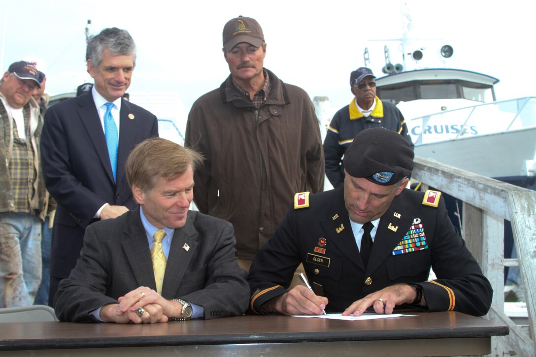 TANGIER ISLAND, Va. -- From left, Congressman Scott Rigell, Gov. Bob McDonnell and Tangier's mayor, James "Ooker" Eskridge, look on as Col. Paul Olsen, Norfolk District commander, signs a proclamation Nov. 20, 2012. The governor and the U.S. Army Corps of Engineers recently announced plans to build a long-awaited jetty to protect the island's endangered harbor. With the Corps' agreement several weeks ago to commit federal funds, a cost-sharing agreement with the Commonwealth was signed and the project approved for study, design and construction. (U.S. Army photo/Kerry Solan)